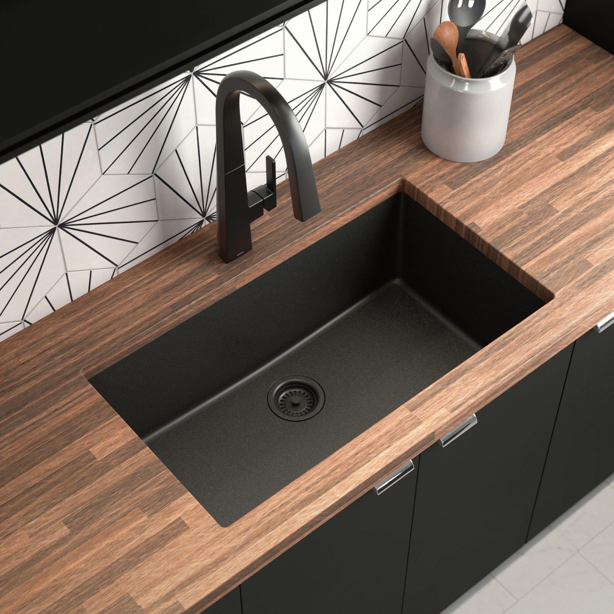 Matte black granite undermount kitchen sink with single bowl and drain, installed in wood countertop.