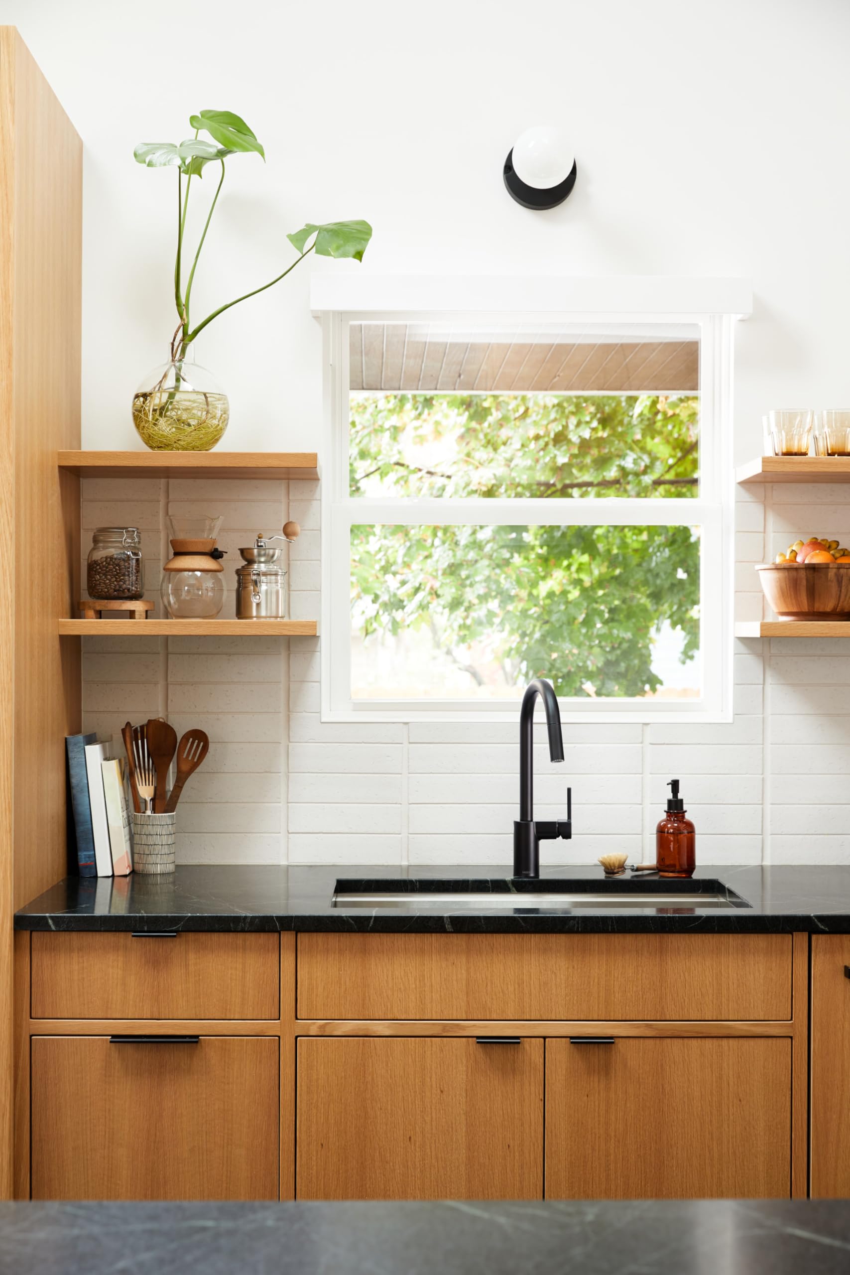 Matte black single-handle pulldown kitchen faucet with high arc spout installed above sink.