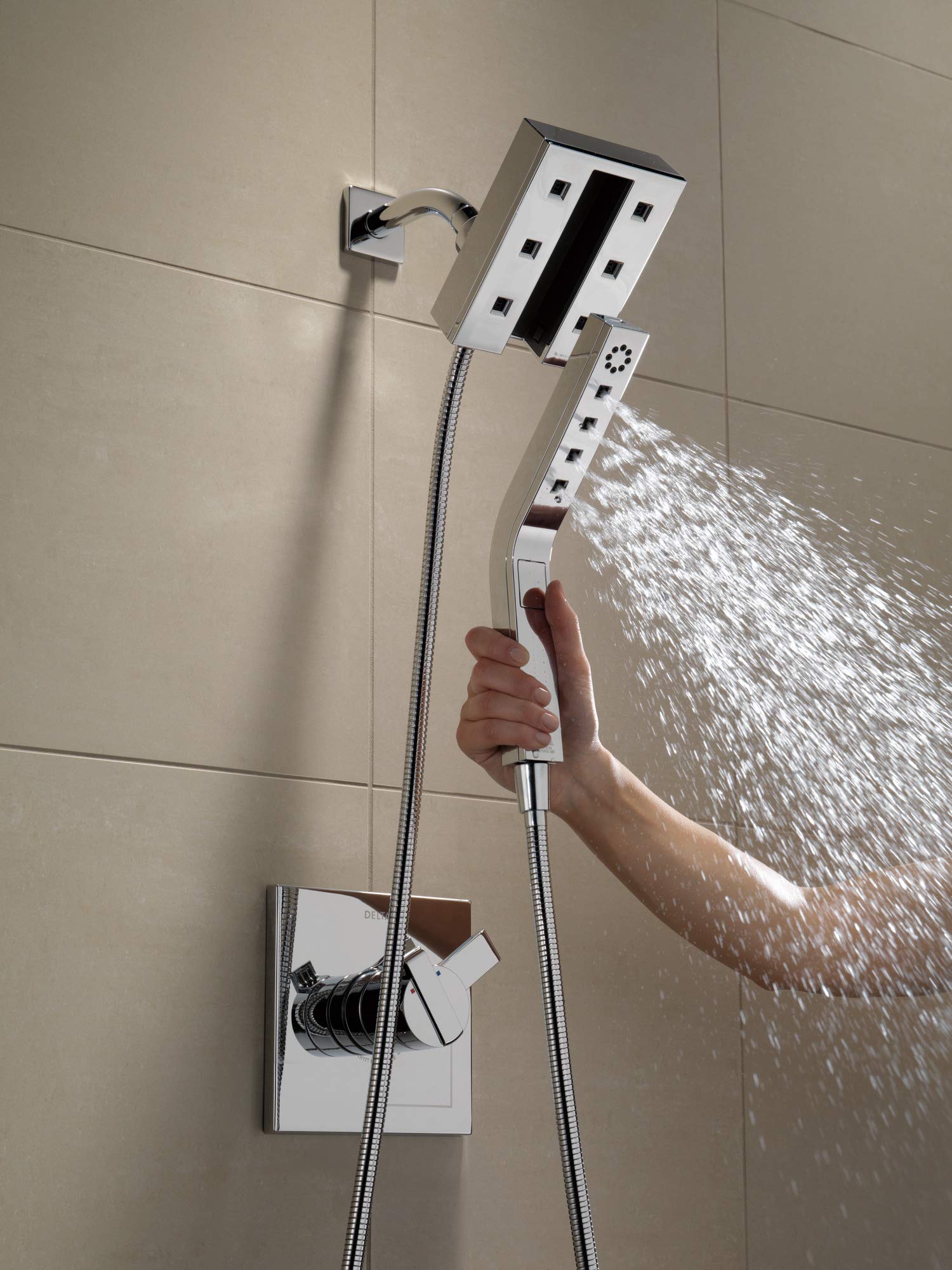 Black stainless steel shower arm with wall-mounted control panel and handheld showerhead spraying water.