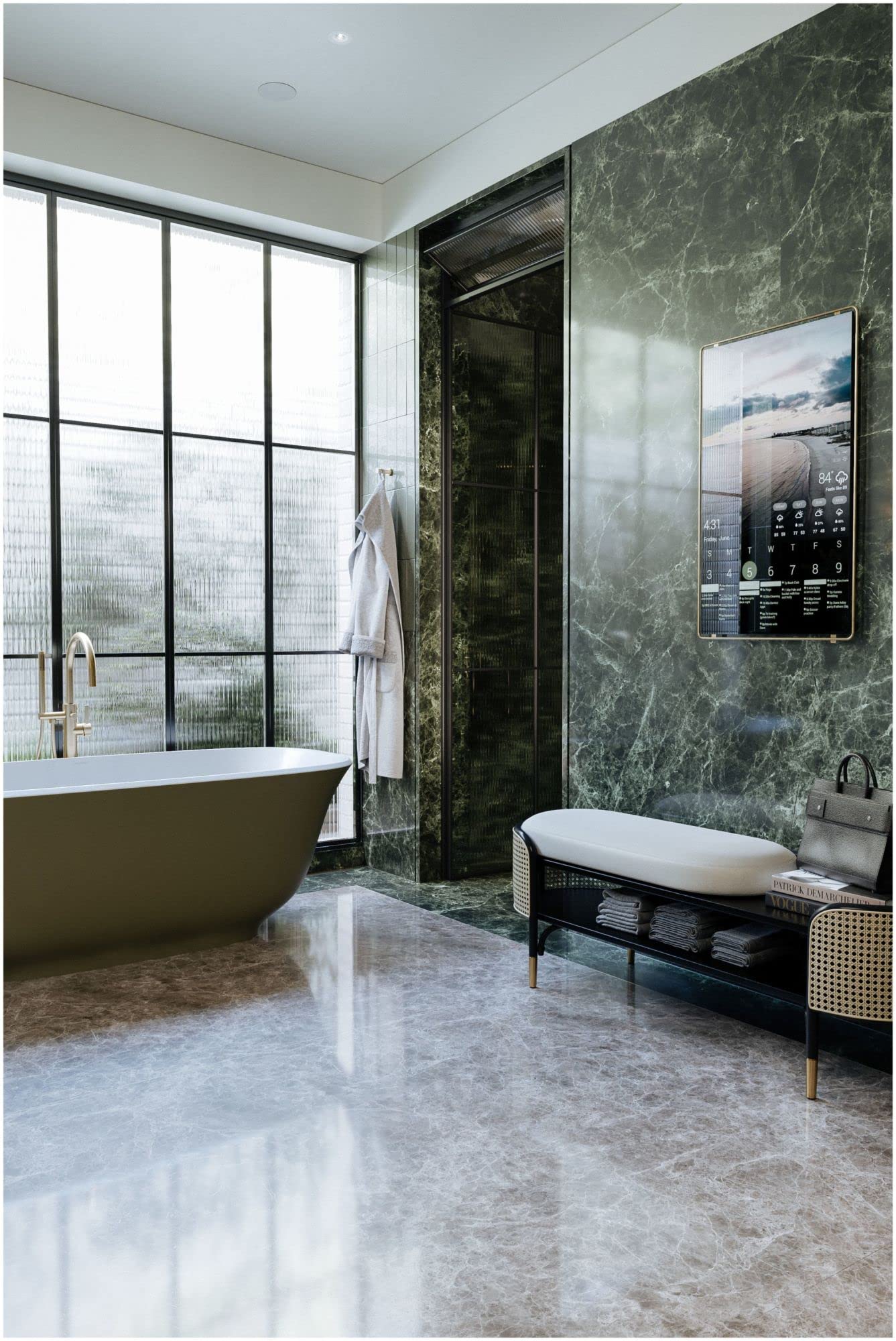 Antique gold robe hook mounted on green marble bathroom wall above bathtub area.