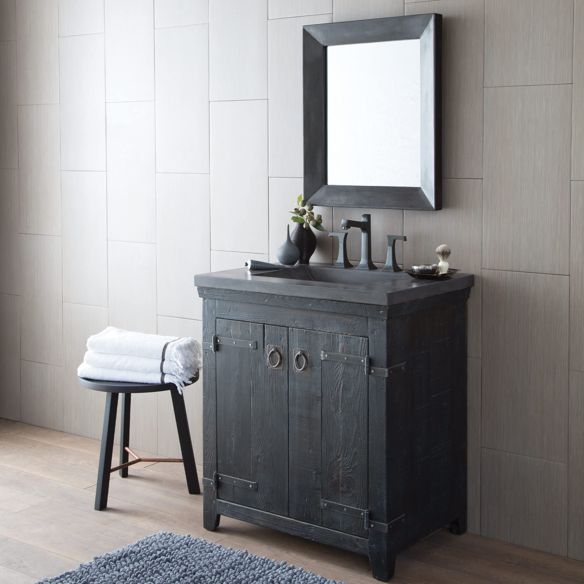 Rectangular wall mirror with dark frame mounted above black bathroom vanity with sink and faucet.