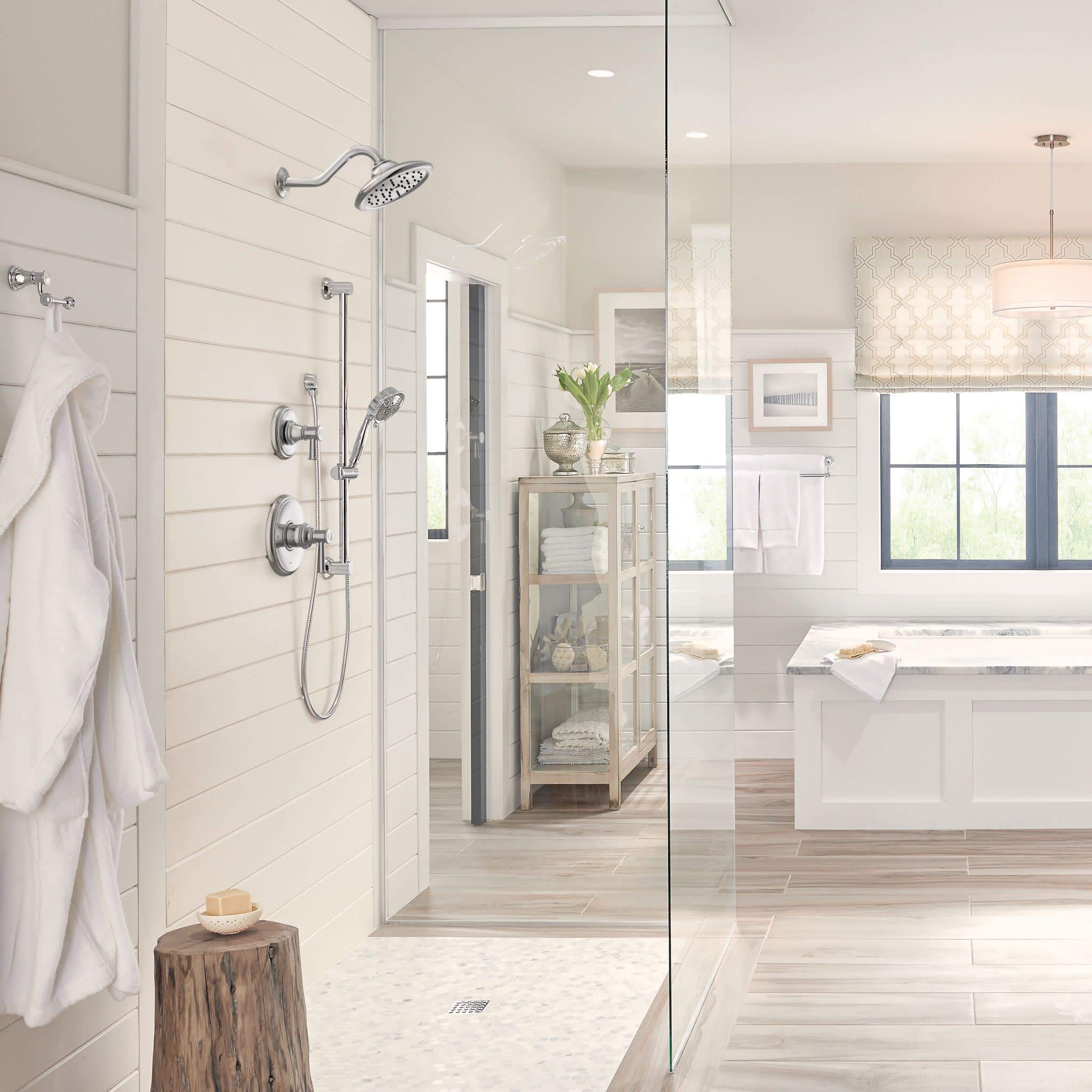 Chrome shower valve trim kit with single handle, overhead rain showerhead, and handheld spray mounted on white subway tile wa