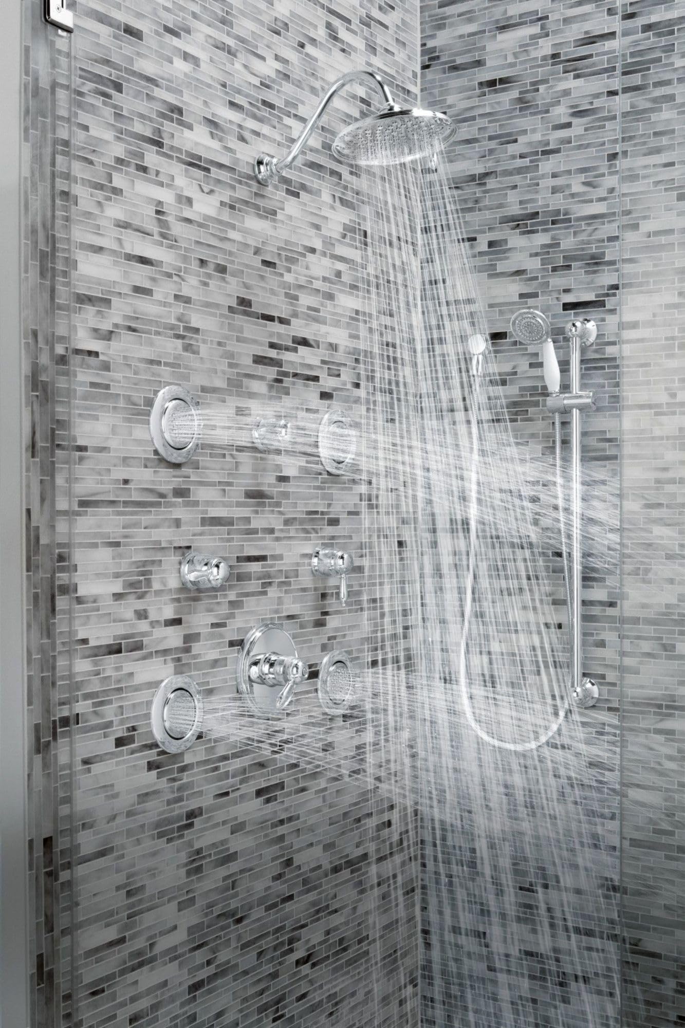 Polished nickel shower system with overhead rainfall showerhead, handheld wand, and body jets mounted on tiled wall with wate