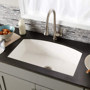 Pearl white farmhouse kitchen sink with single rectangular basin and brushed nickel faucet installed in black countertop.