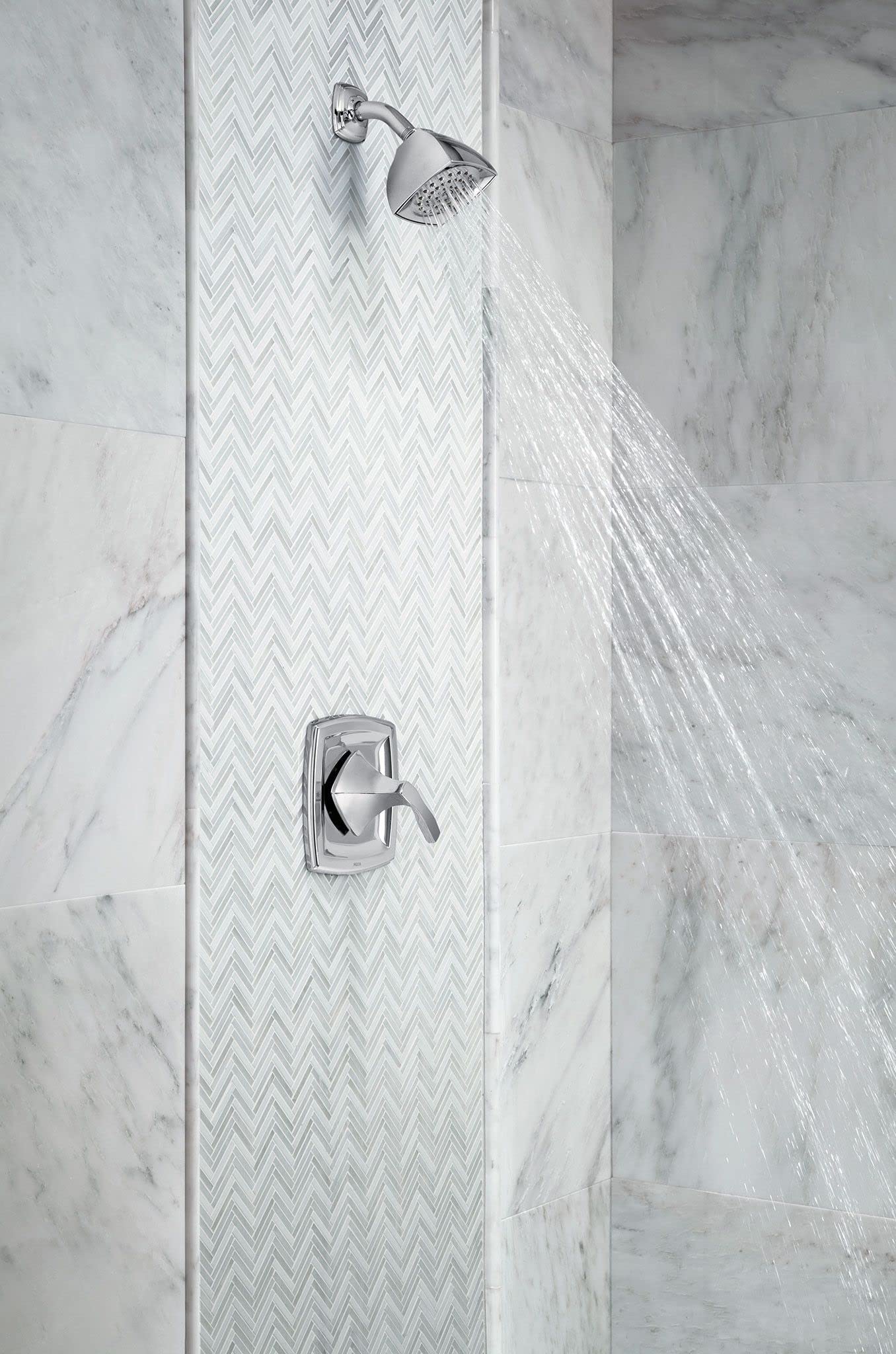 Nickel shower valve trim with single lever handle and round showerhead mounted on marble tile wall.