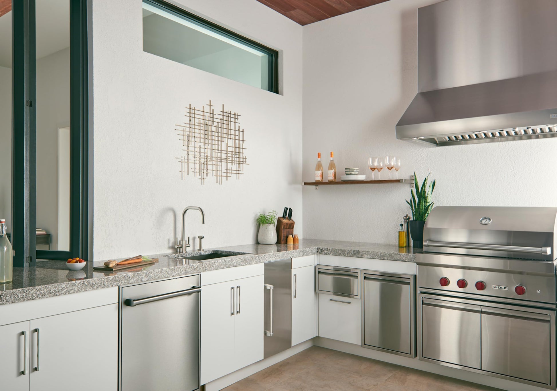 Brushed stainless steel single bowl sink installed in modern kitchen with white cabinetry and granite countertop.