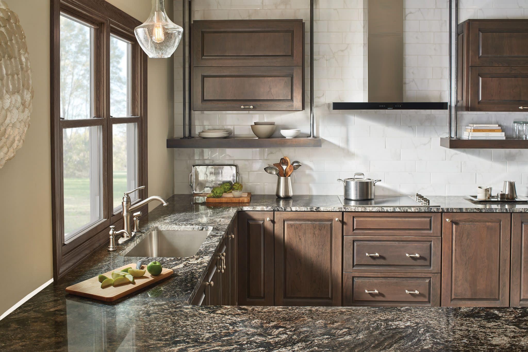 Stainless steel traditional kitchen faucet with high arc spout and single handle mounted on granite countertop.