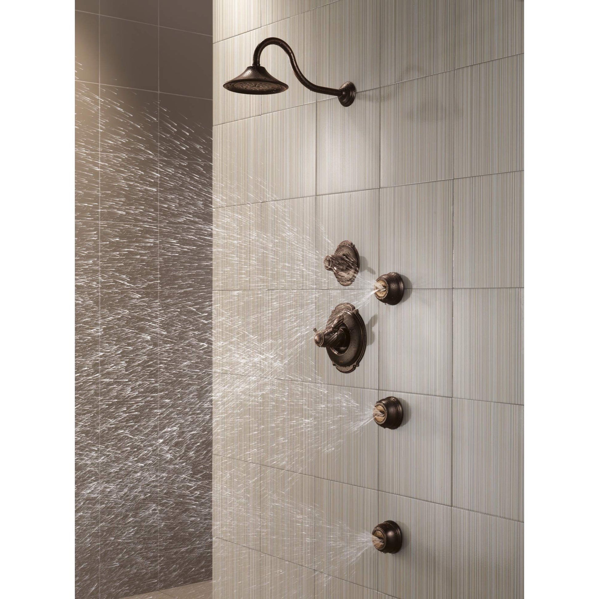 Venetian bronze shower system with curved arm, round shower head, and multiple wall-mounted control knobs installed in tiled 