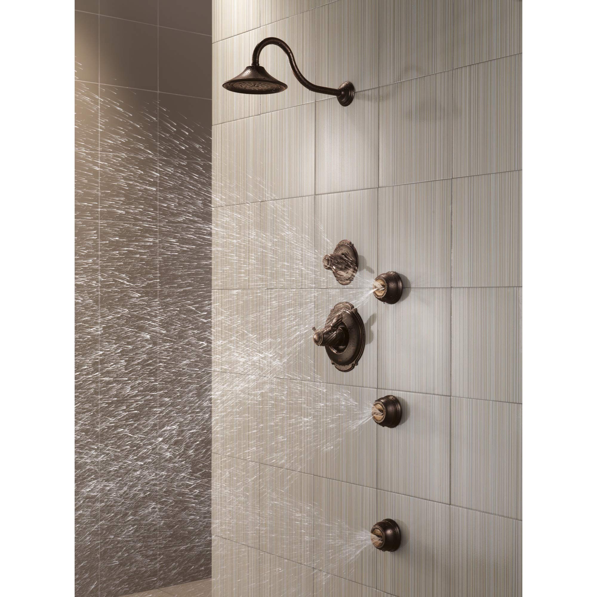 Venetian bronze shower system with curved arm, round shower head, and multiple wall-mounted control knobs installed in tiled 