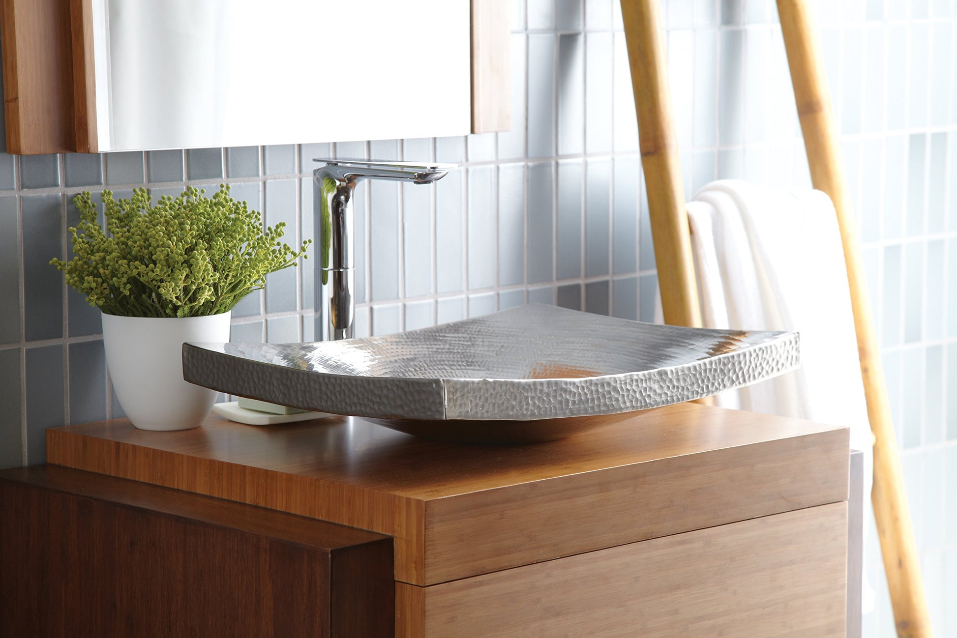 Brushed nickel vessel sink with textured surface and chrome faucet mounted on wood vanity.