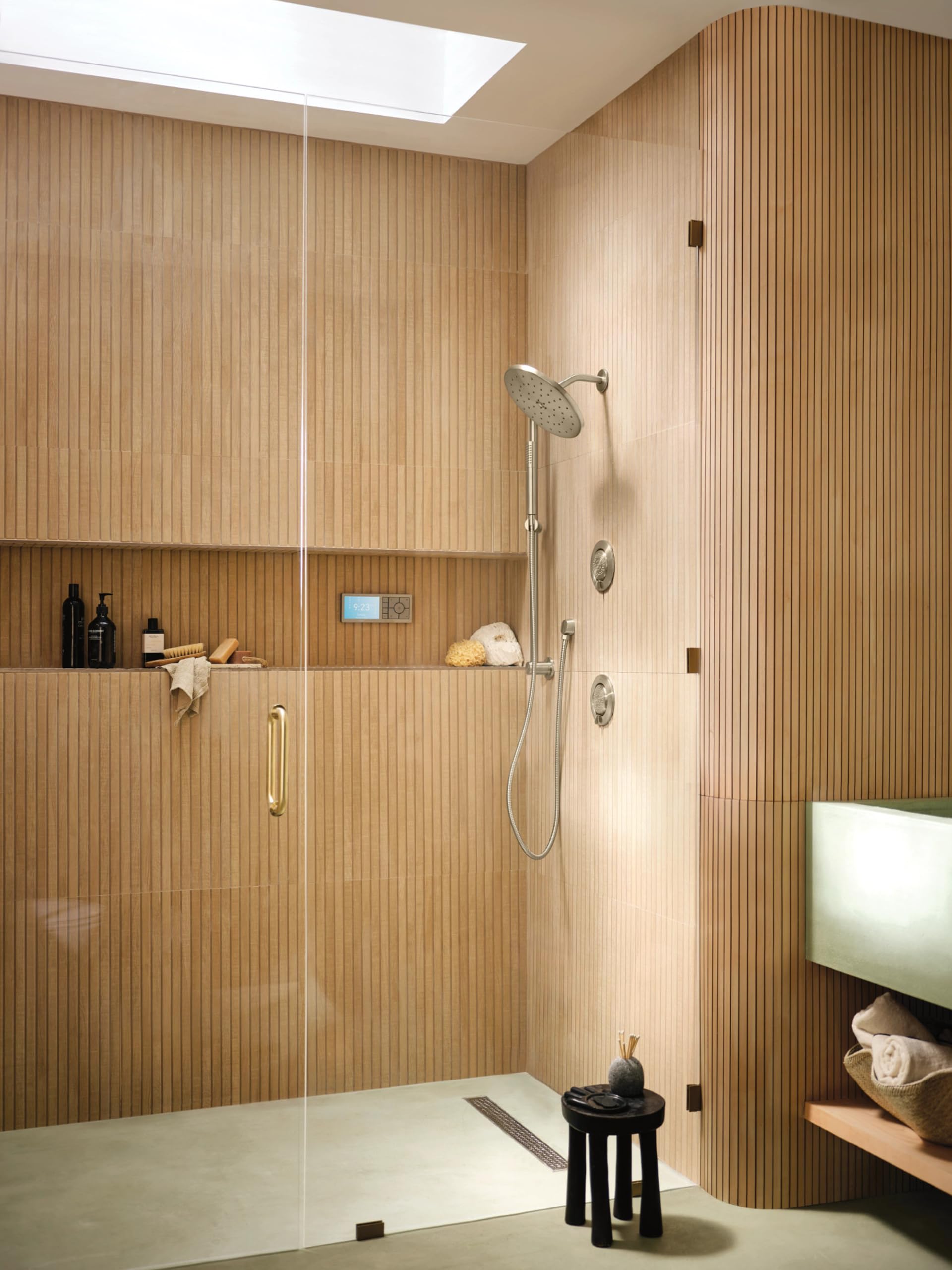 Brushed nickel handheld shower system with round showerhead, slide bar, and metal hose installed in bathroom shower enclosure