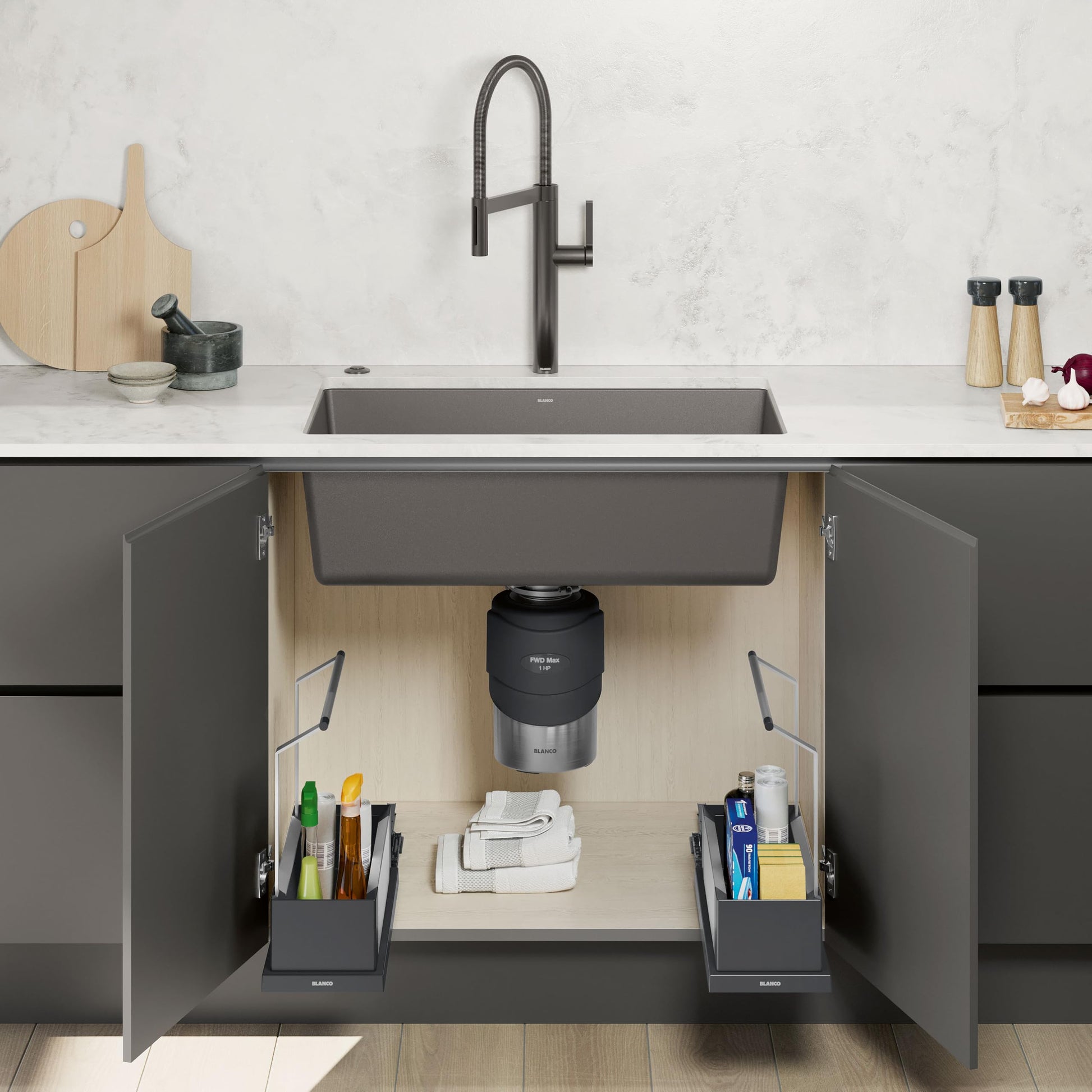 Black food waste disposal unit installed under kitchen sink with gray top and stainless steel base.