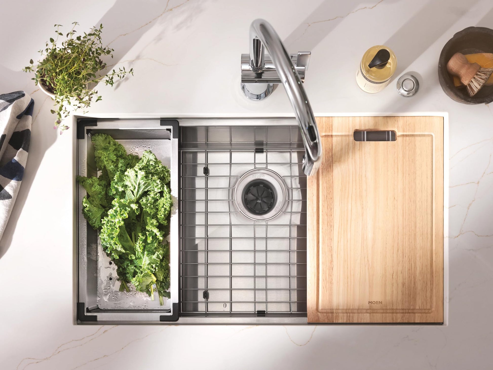 Stainless steel undermount sink with colander, bottom grid, wooden cutting board, and flexible drying rack, viewed from above