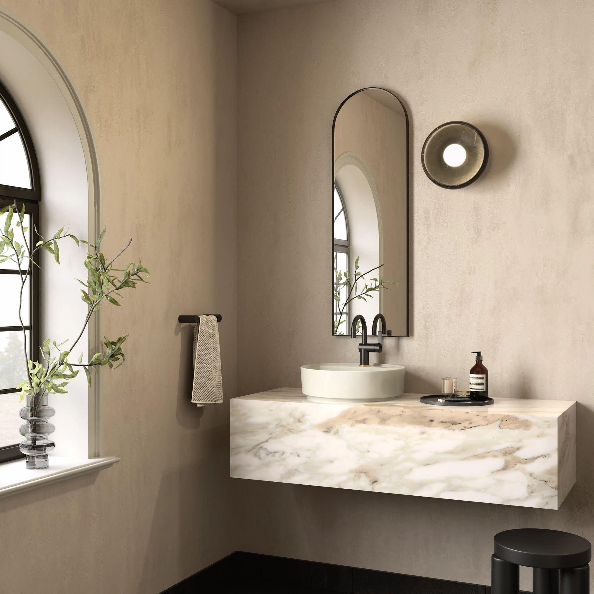 Matte black single-handle bathroom faucet with curved spout mounted above white round sink on marble countertop.