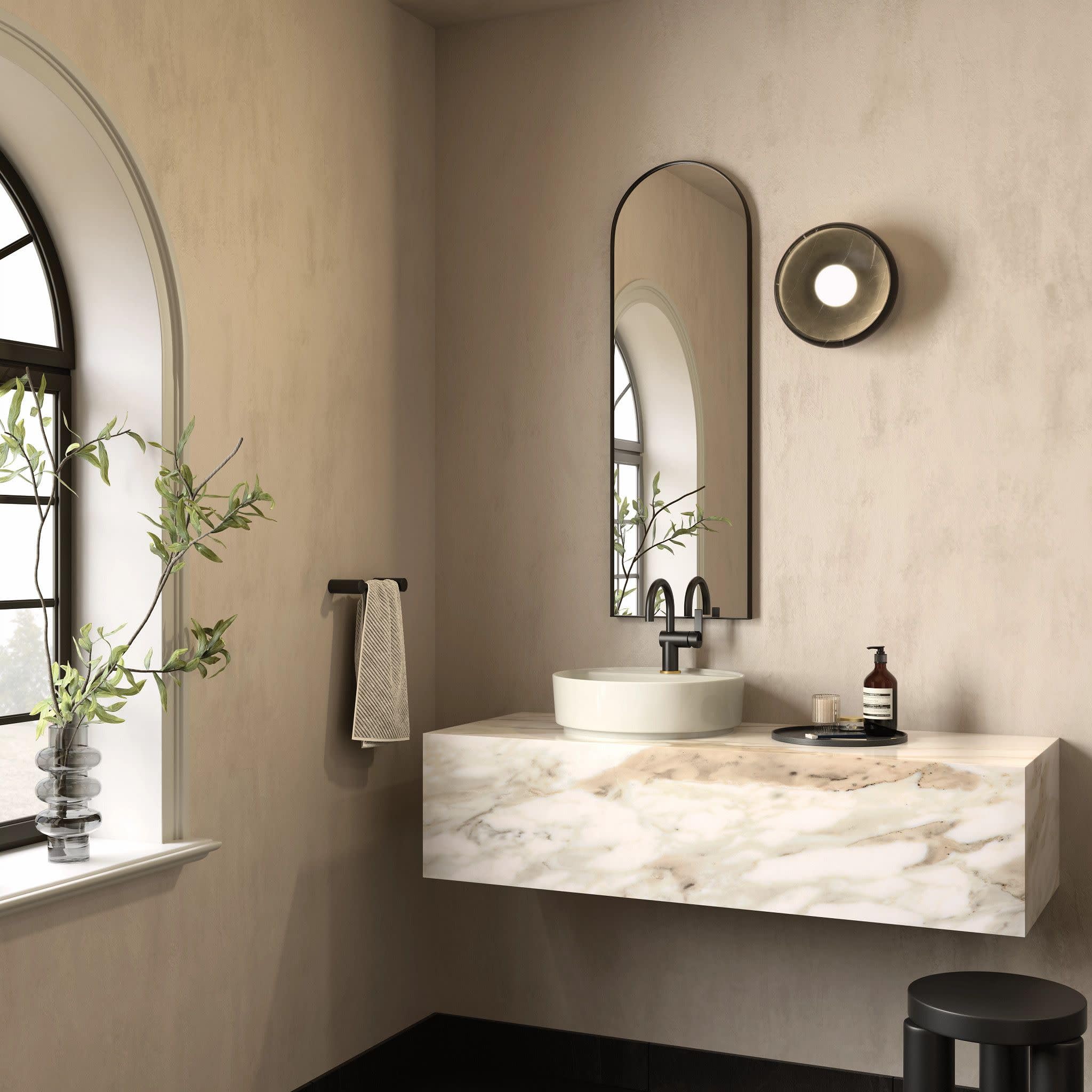 Matte black single-handle bathroom faucet with curved spout mounted above white round sink on marble countertop.