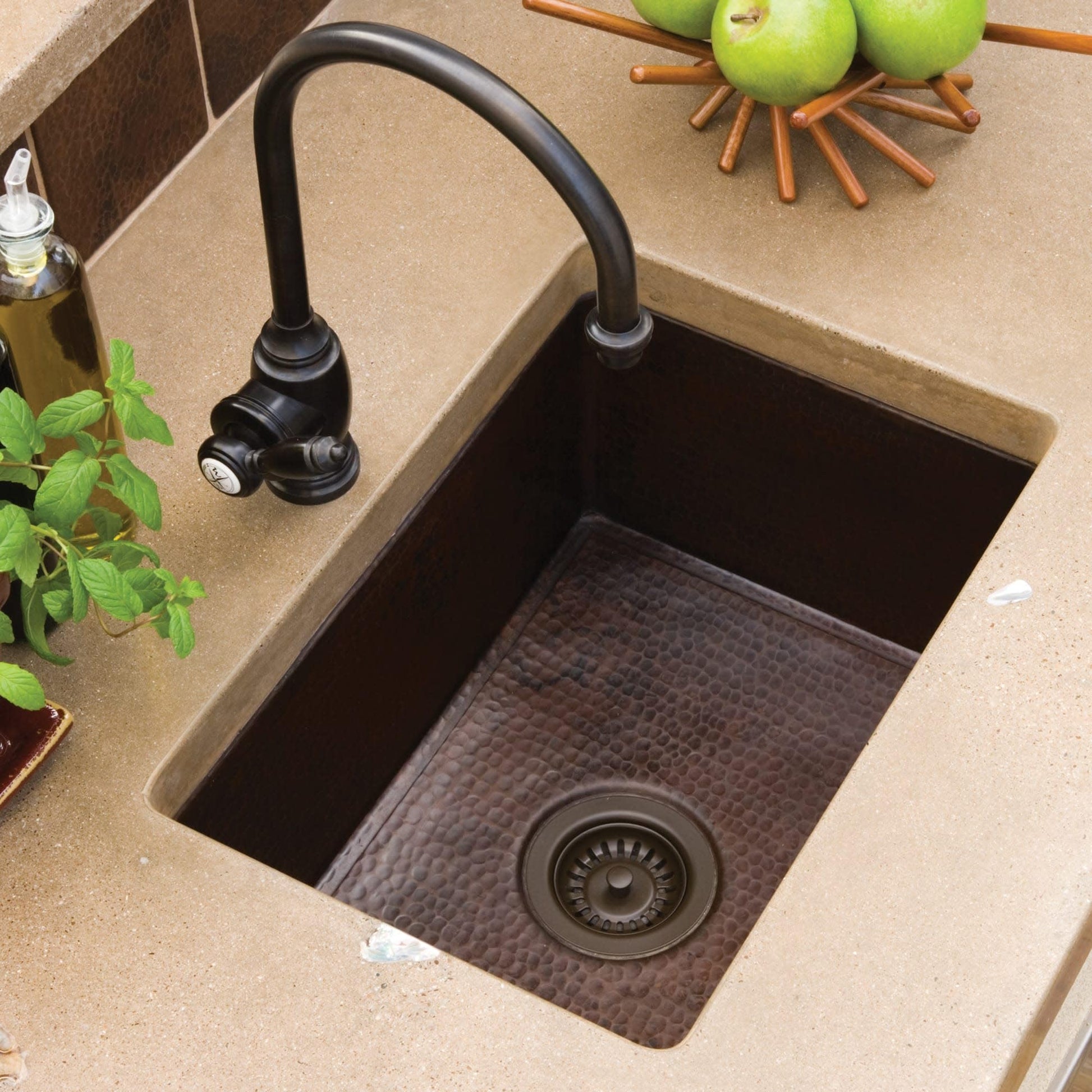 Antique copper single-bowl kitchen sink with hammered interior texture, drain, and black gooseneck faucet installed in counte