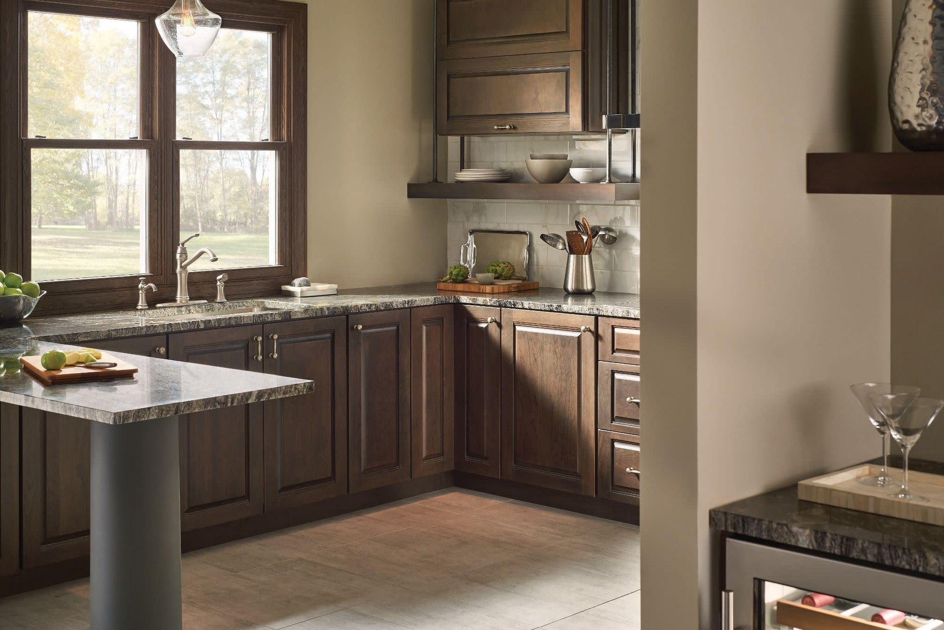 Stainless steel kitchen faucet with high arc spout and single handle mounted on granite countertop in dark wood cabinetry.