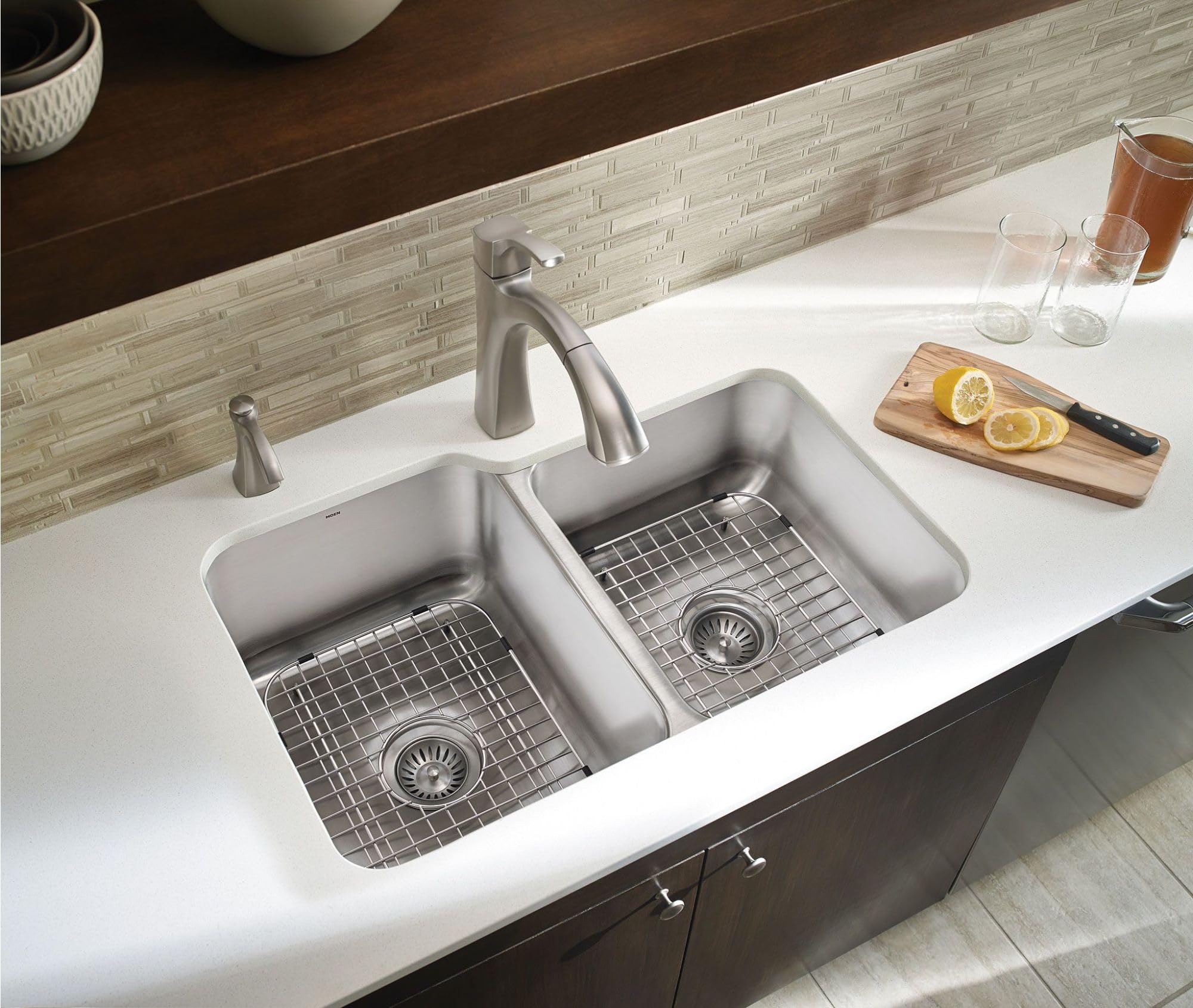 Stainless steel soap dispenser mounted on kitchen sink countertop next to faucet.