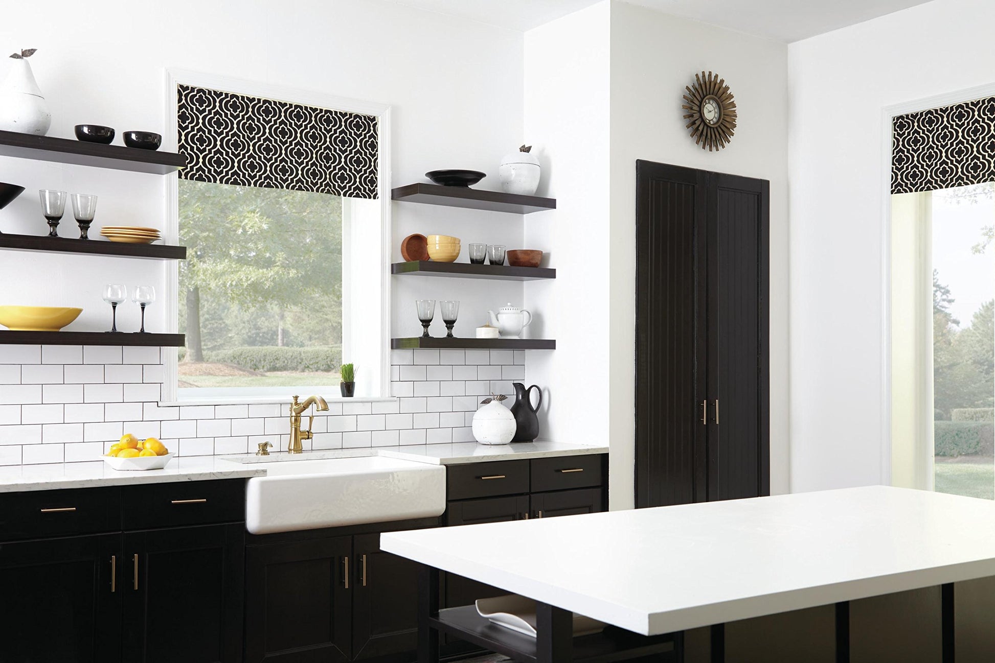 Champagne bronze single handle pull-out kitchen faucet mounted above white farmhouse sink in black and white kitchen.