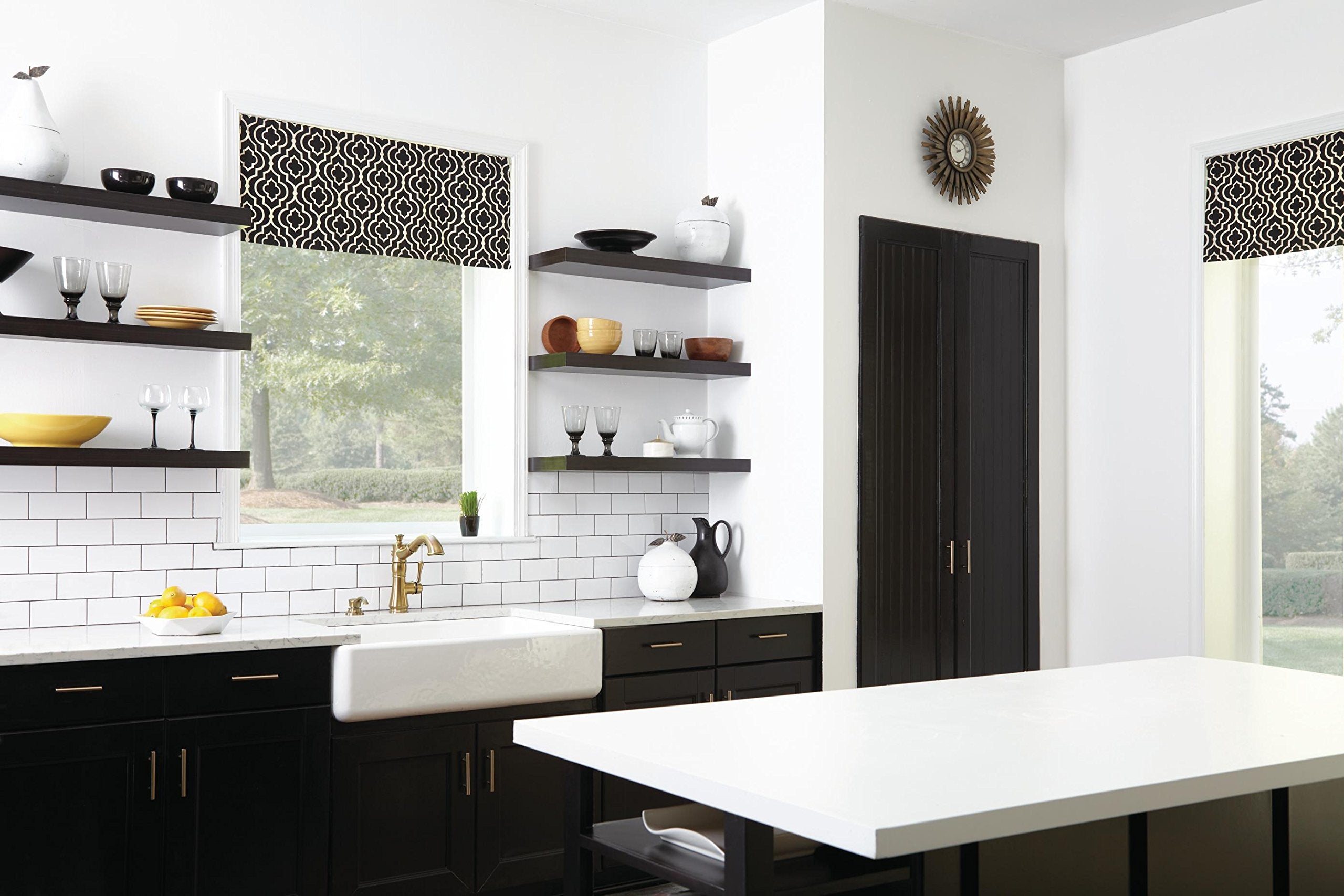 Champagne bronze single handle pull-out kitchen faucet mounted above white farmhouse sink in black and white kitchen.