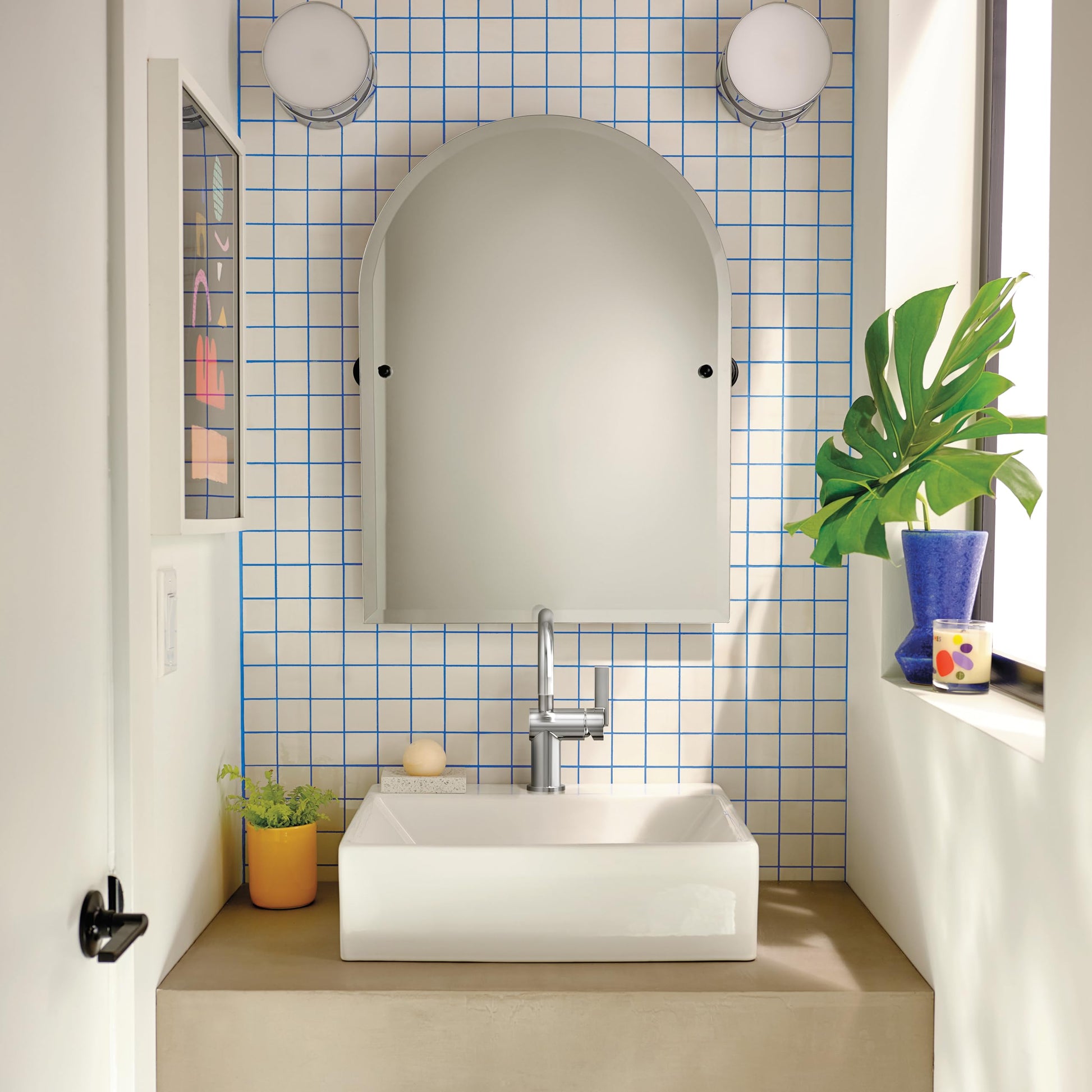 Chrome single-handle bathroom faucet installed on white rectangular sink in tiled bathroom vanity.