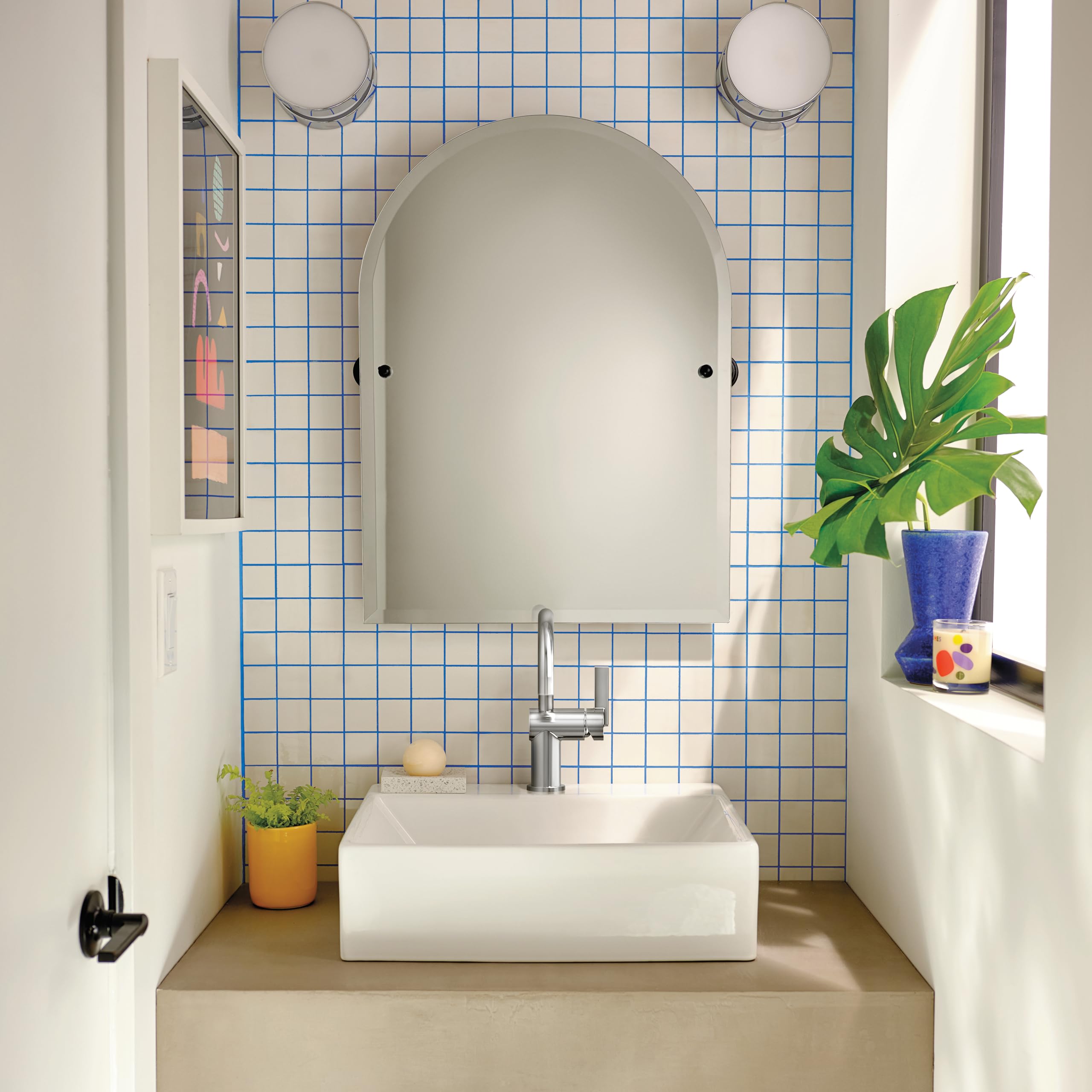 Chrome single-handle bathroom faucet installed on white rectangular sink in tiled bathroom vanity.