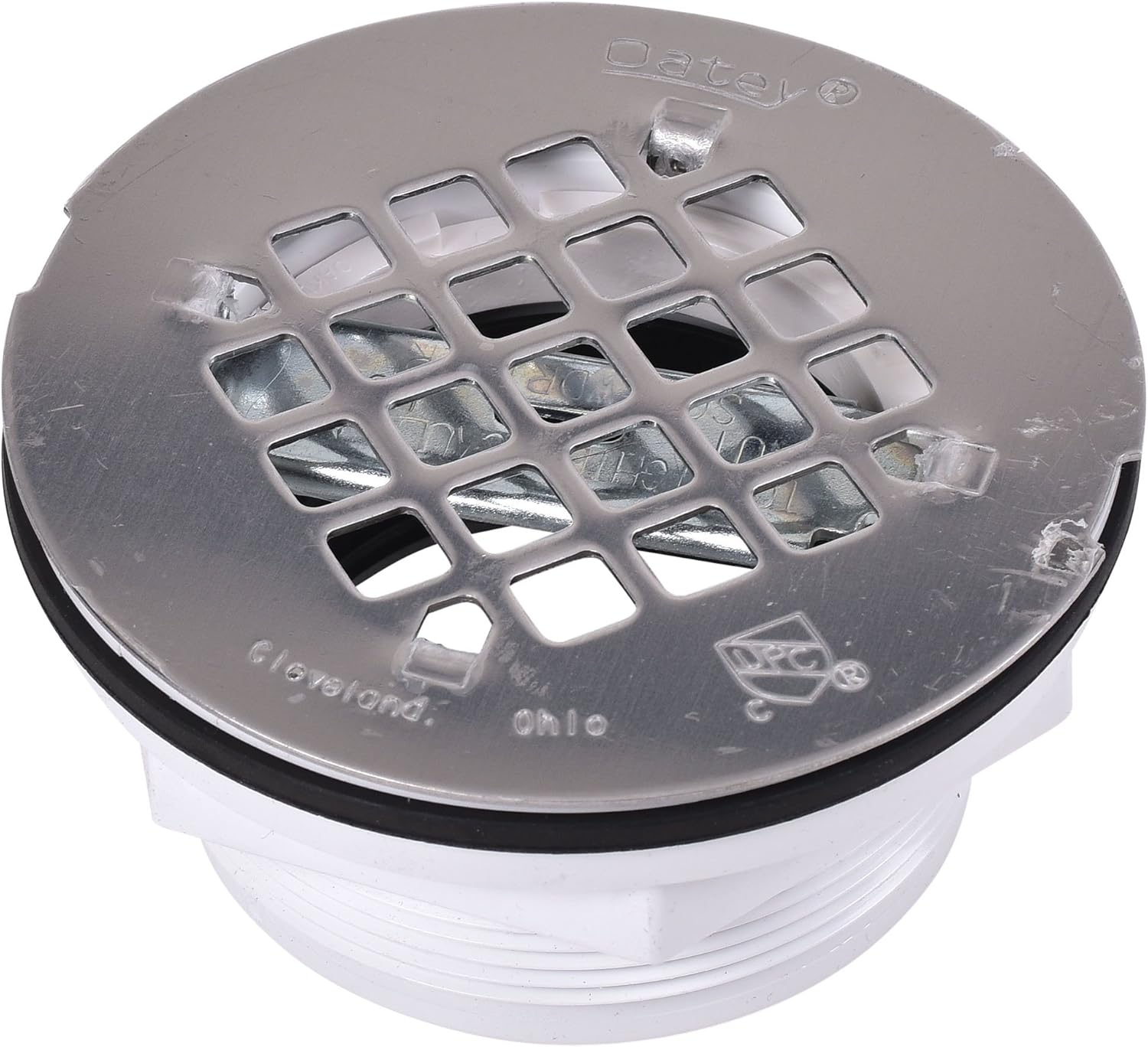 Stainless steel shower drain strainer with grid pattern holes, mounted on white PVC collar with black rubber ring.