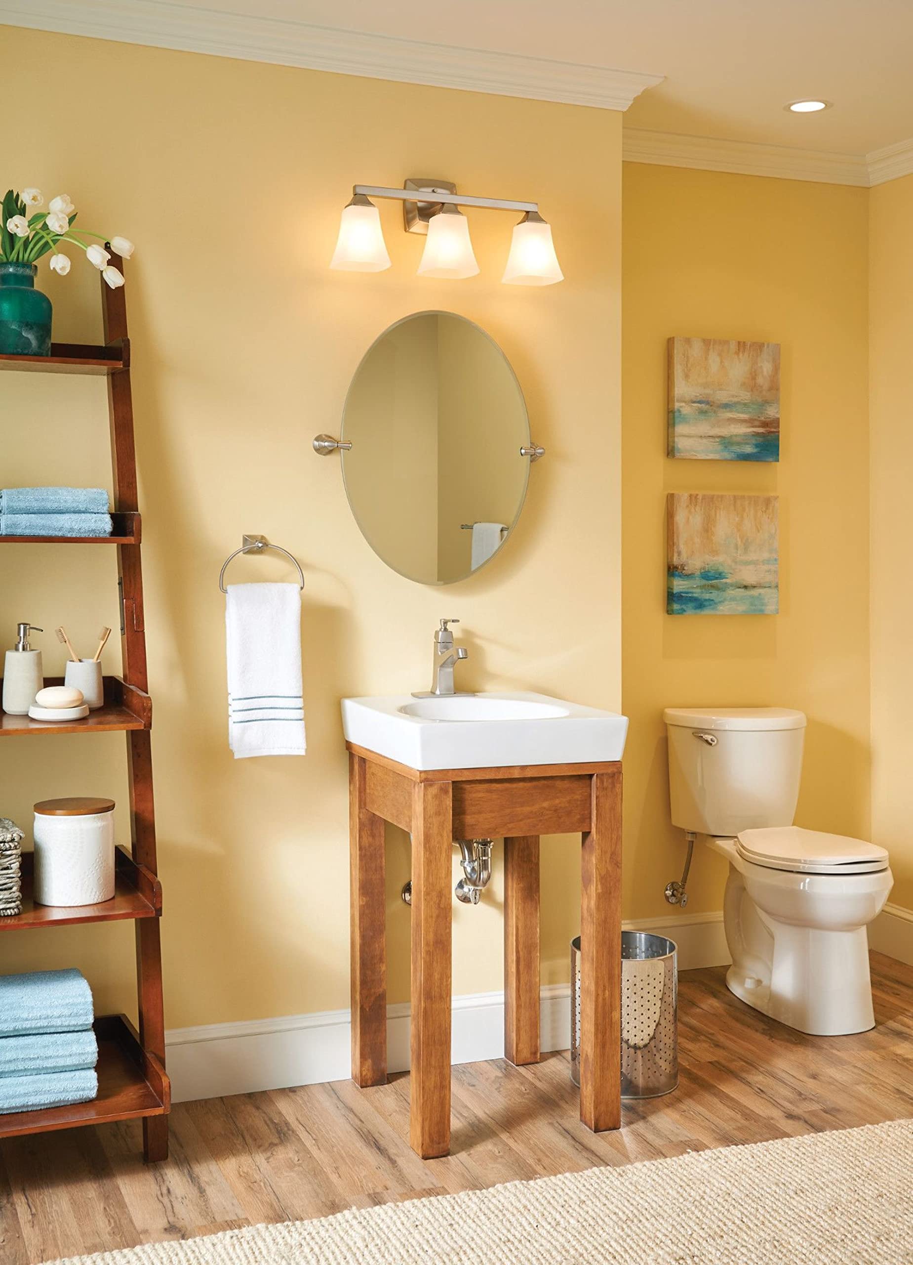 Brushed nickel wall-mount towel ring displayed below oval mirror in bathroom setting.