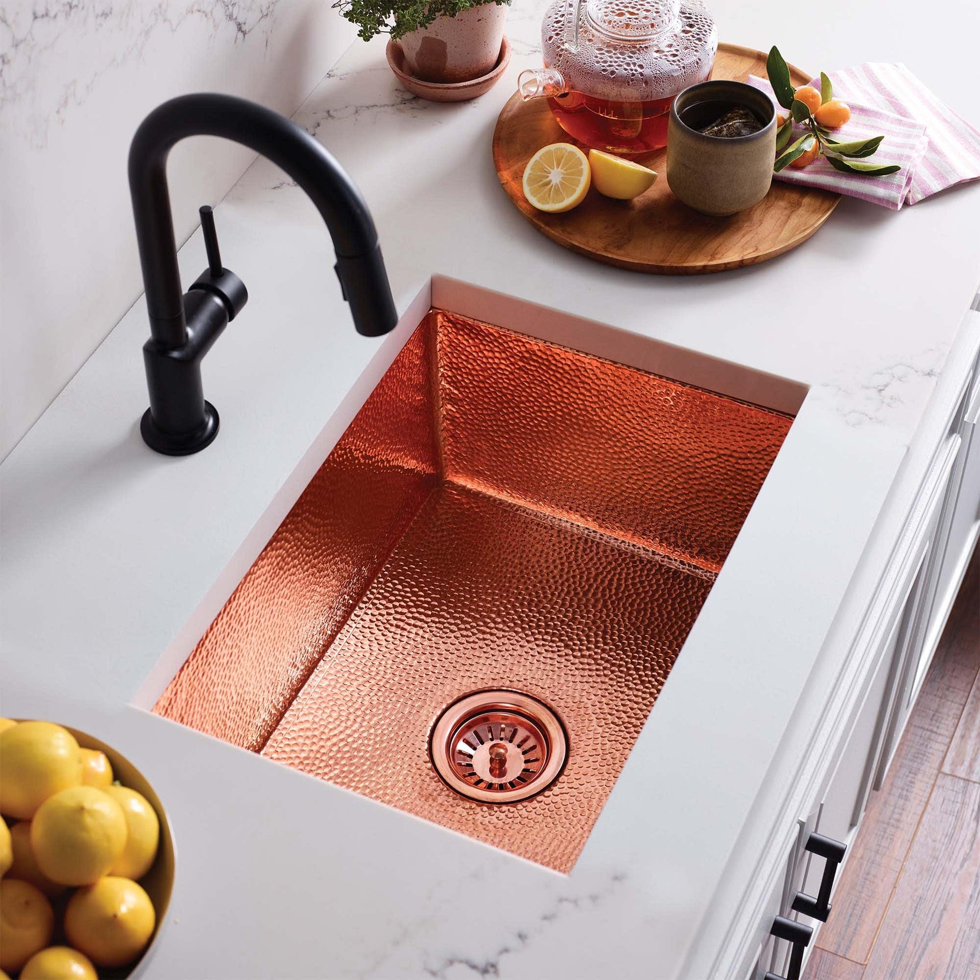Antique copper single-basin kitchen sink with hammered texture and matching drain, paired with black pull-down faucet.