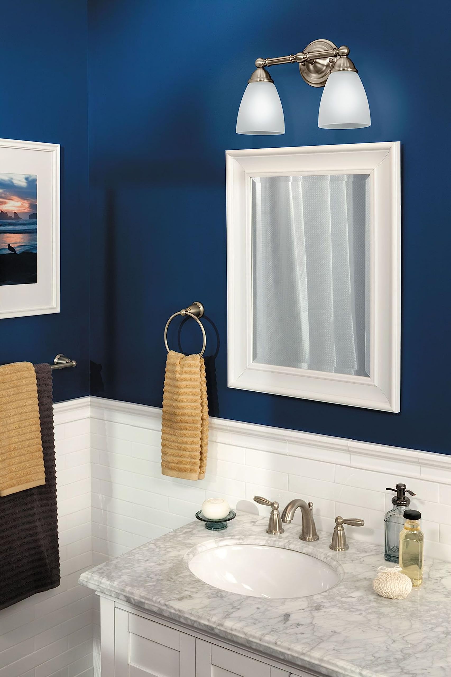 Brushed nickel wall-mount towel ring with spherical finial mounted on blue bathroom wall.