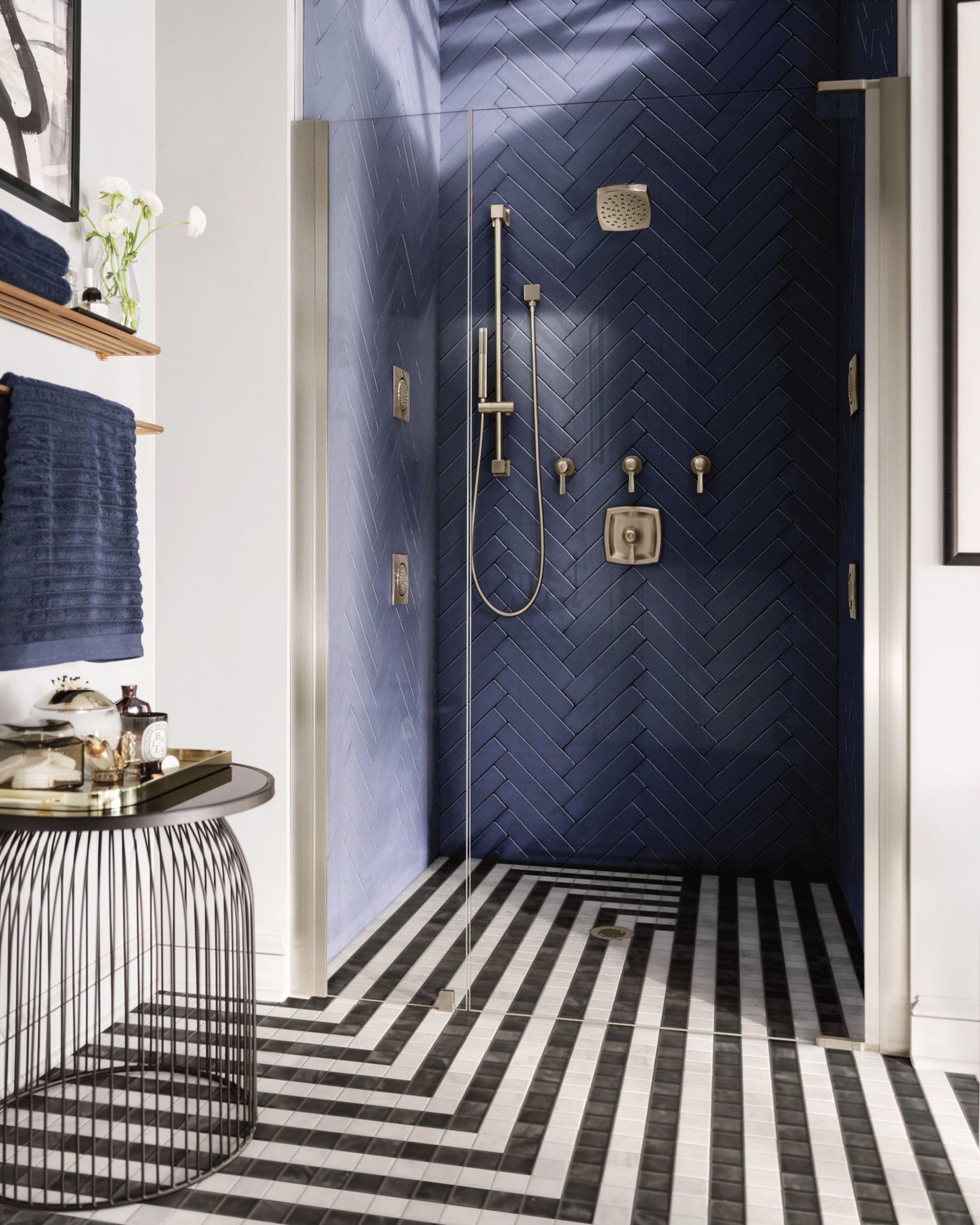 Brushed nickel shower valve trim kit with control handle, diverter, and showerhead mounted on black herringbone tile wall.