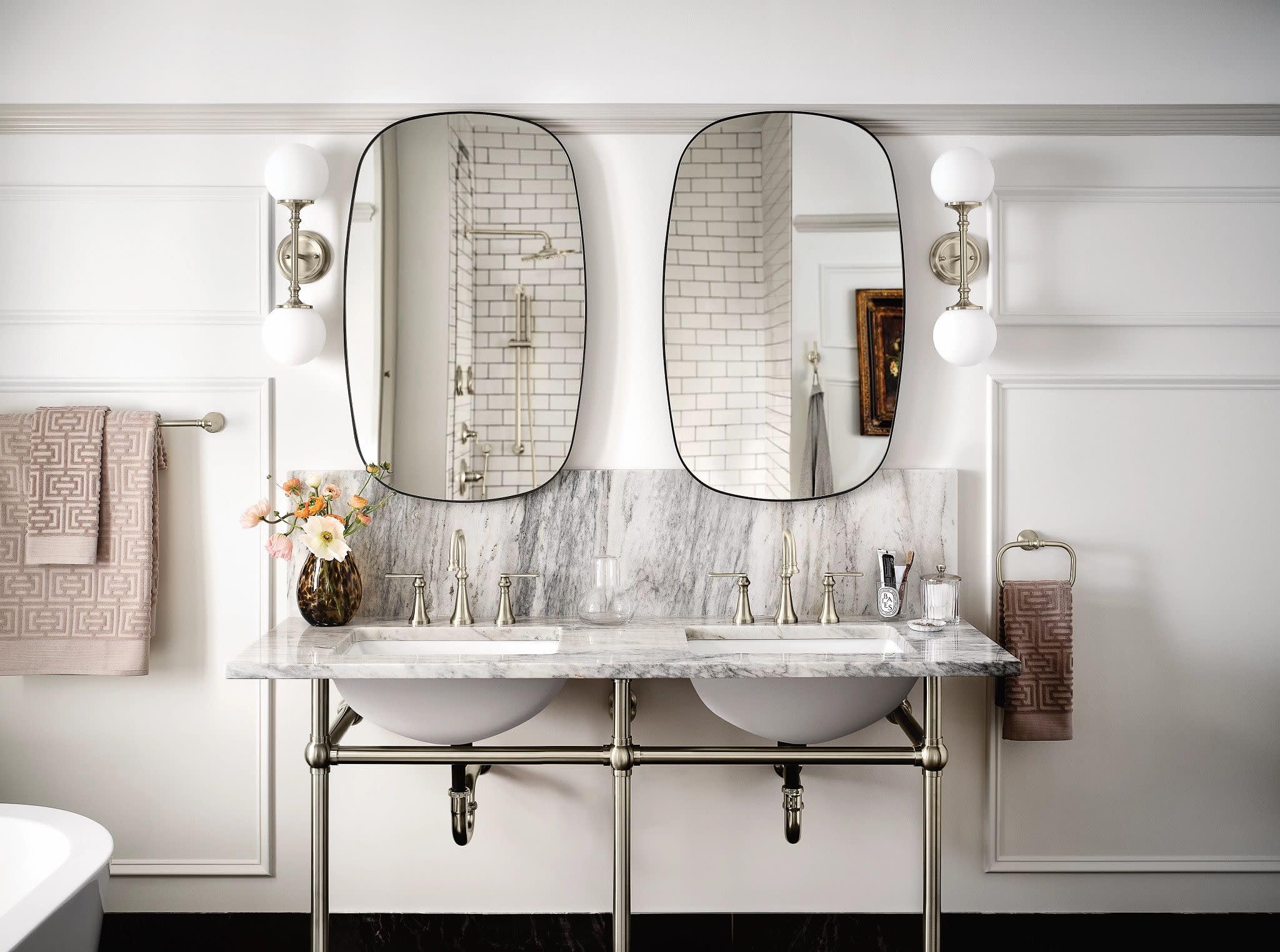 Brushed nickel two-handle widespread bathroom faucet with high arc spout and lever handles installed on marble countertop.