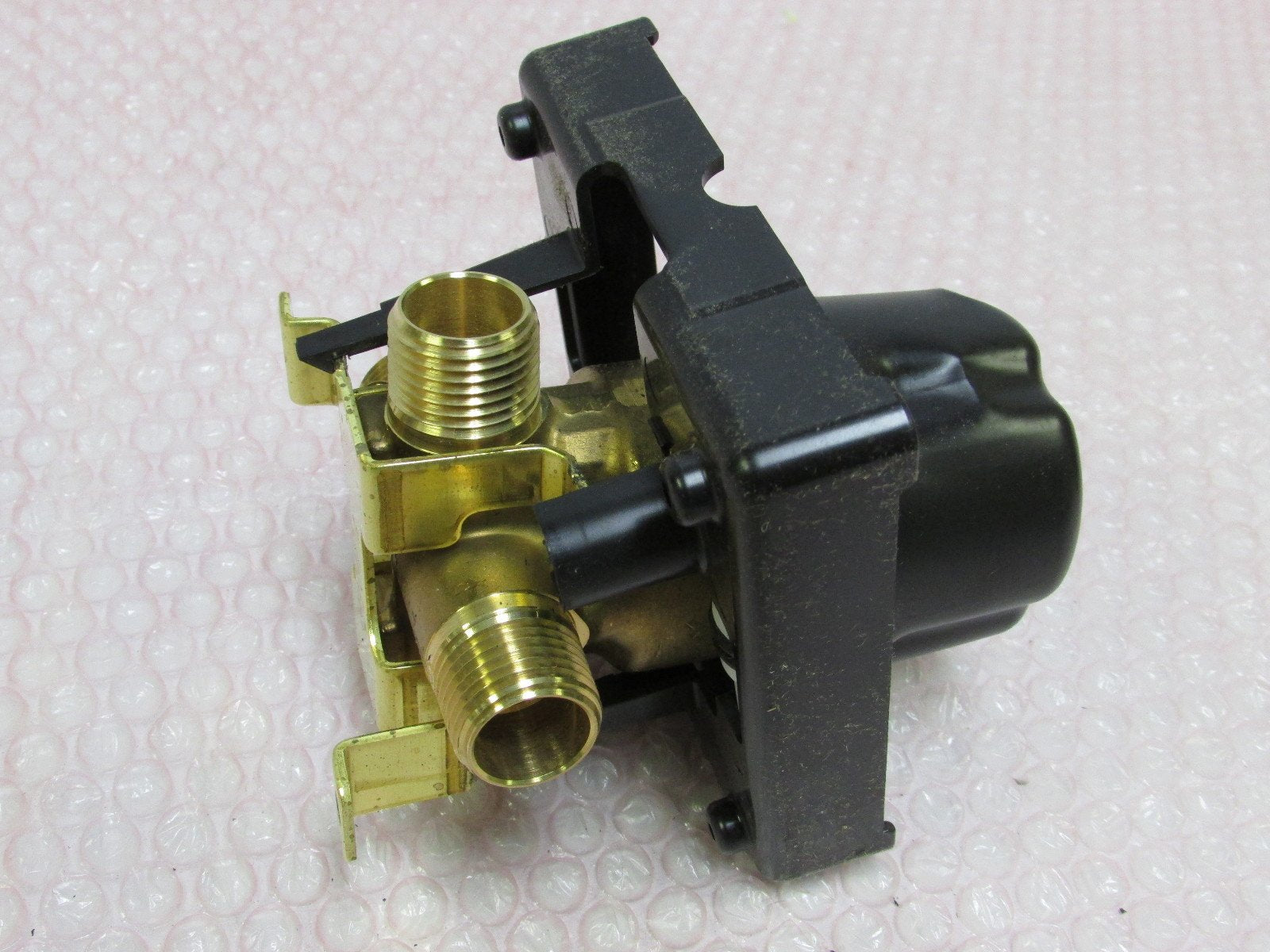 Brass valve body with black plastic housing and two threaded inlet ports for tub/shower rough installation.