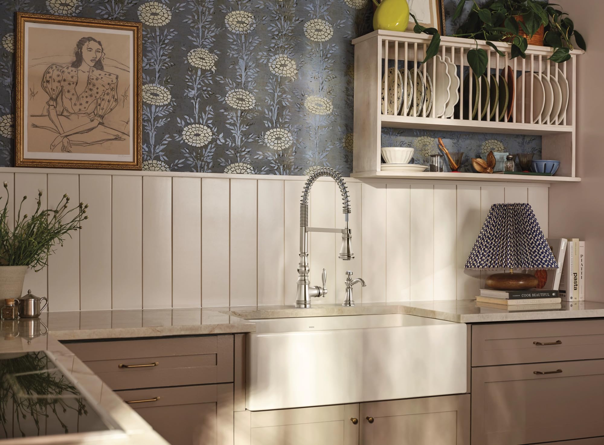 Polished nickel pulldown kitchen faucet with single handle and curved pre-rinse spray arm above farmhouse sink.