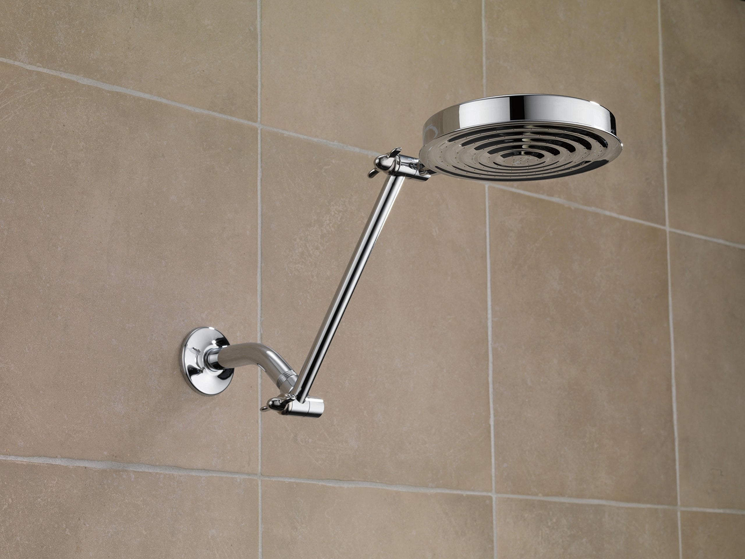 Chrome shower arm with circular showerhead mounted on tiled bathroom wall.