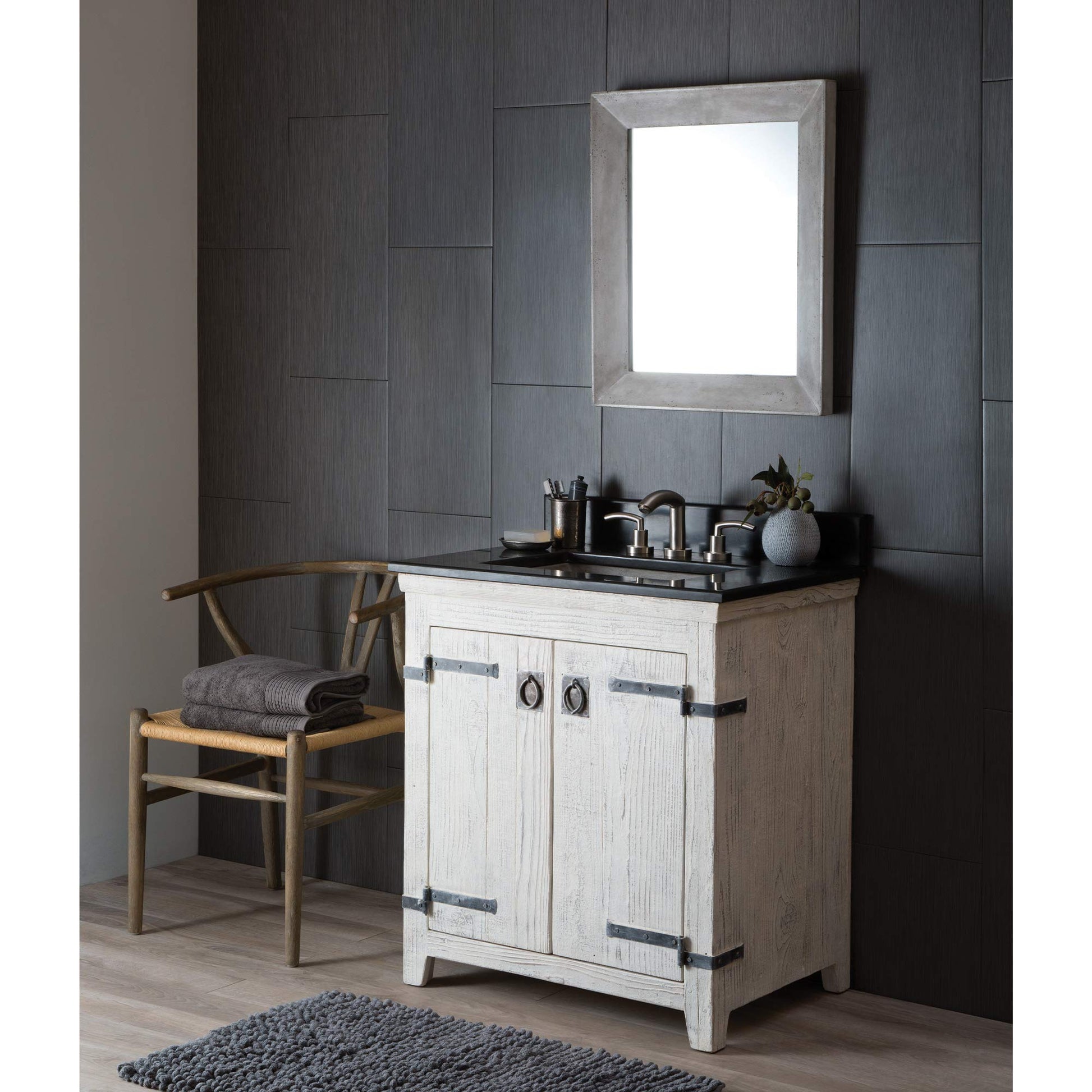 Rectangular mirror with ash-colored wooden frame mounted on dark textured wall above bathroom vanity.