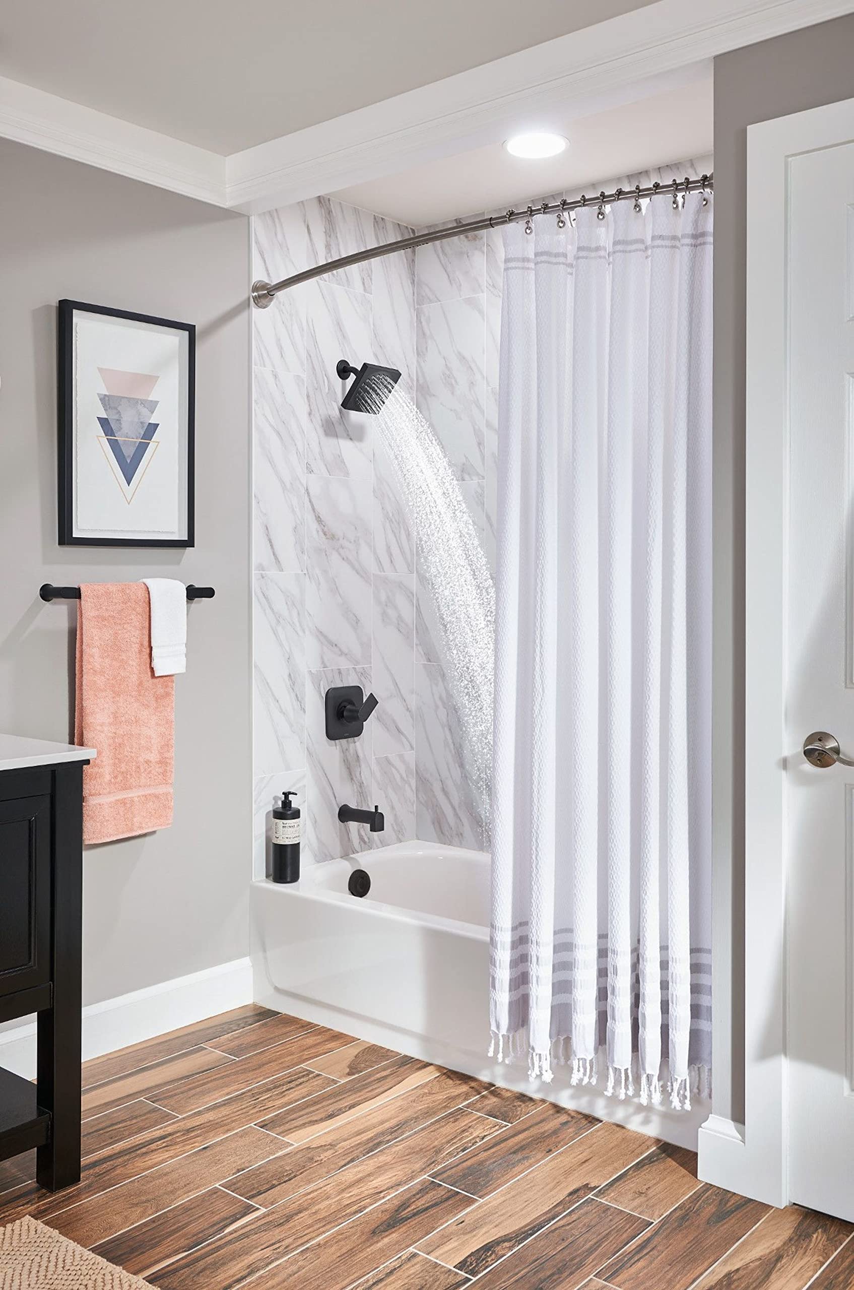 Black wall-mounted towel bar holding folded towels above bathroom sink.