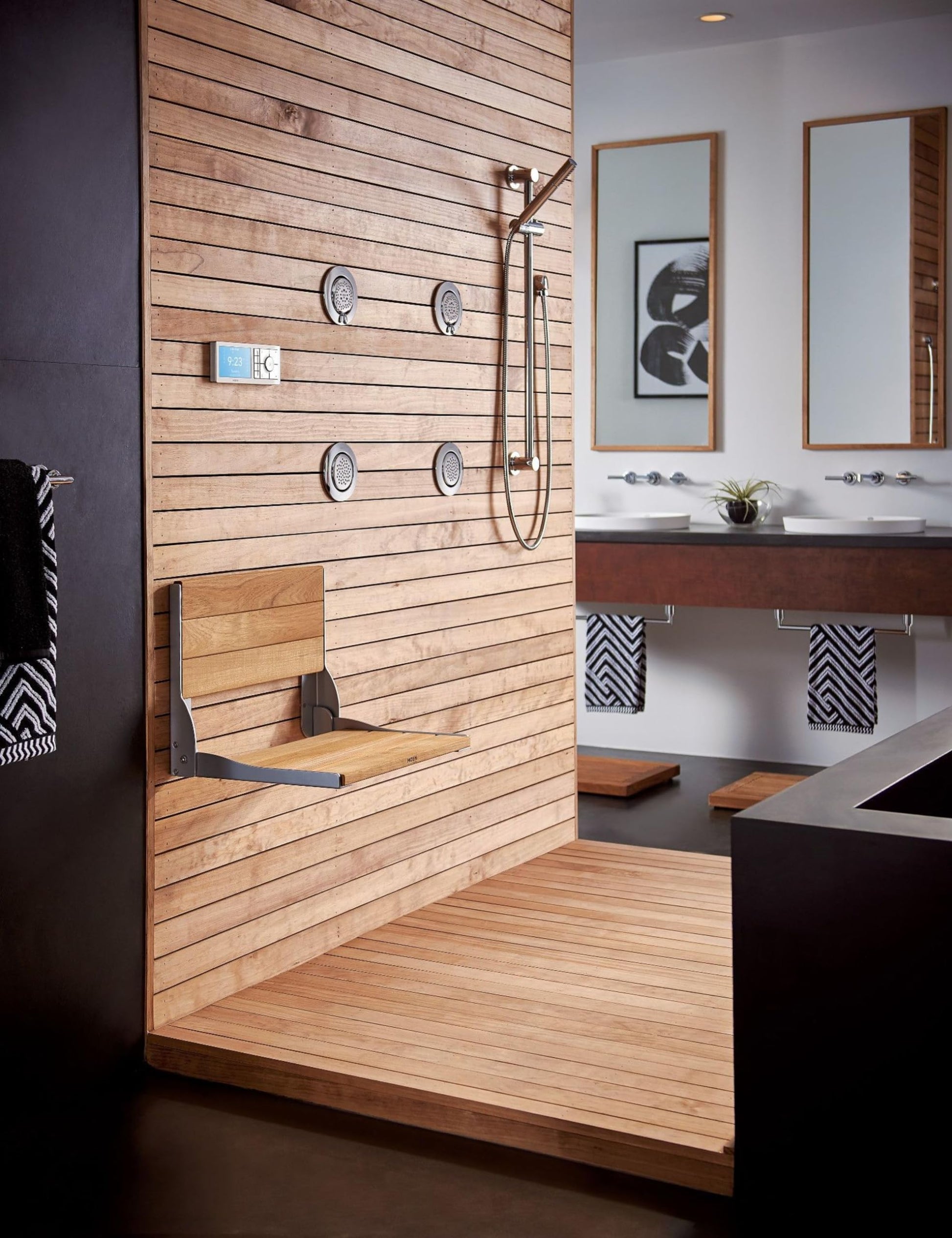 Chrome handheld showerhead with curved metal hose and adjustable slide bar mounted on wooden shower wall.