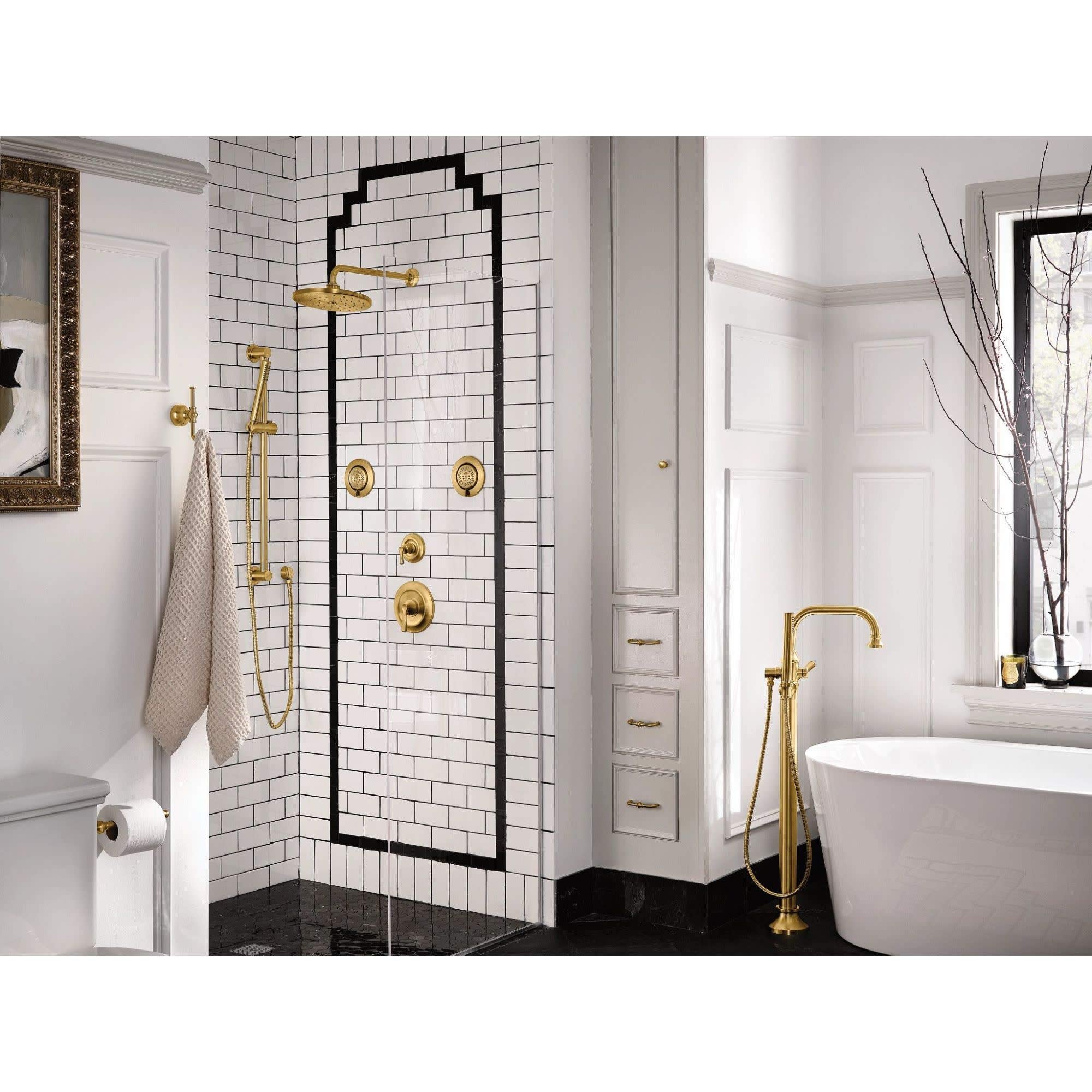 Matte black freestanding tub filler with single handle and attached handshower, shown installed next to white soaking tub.