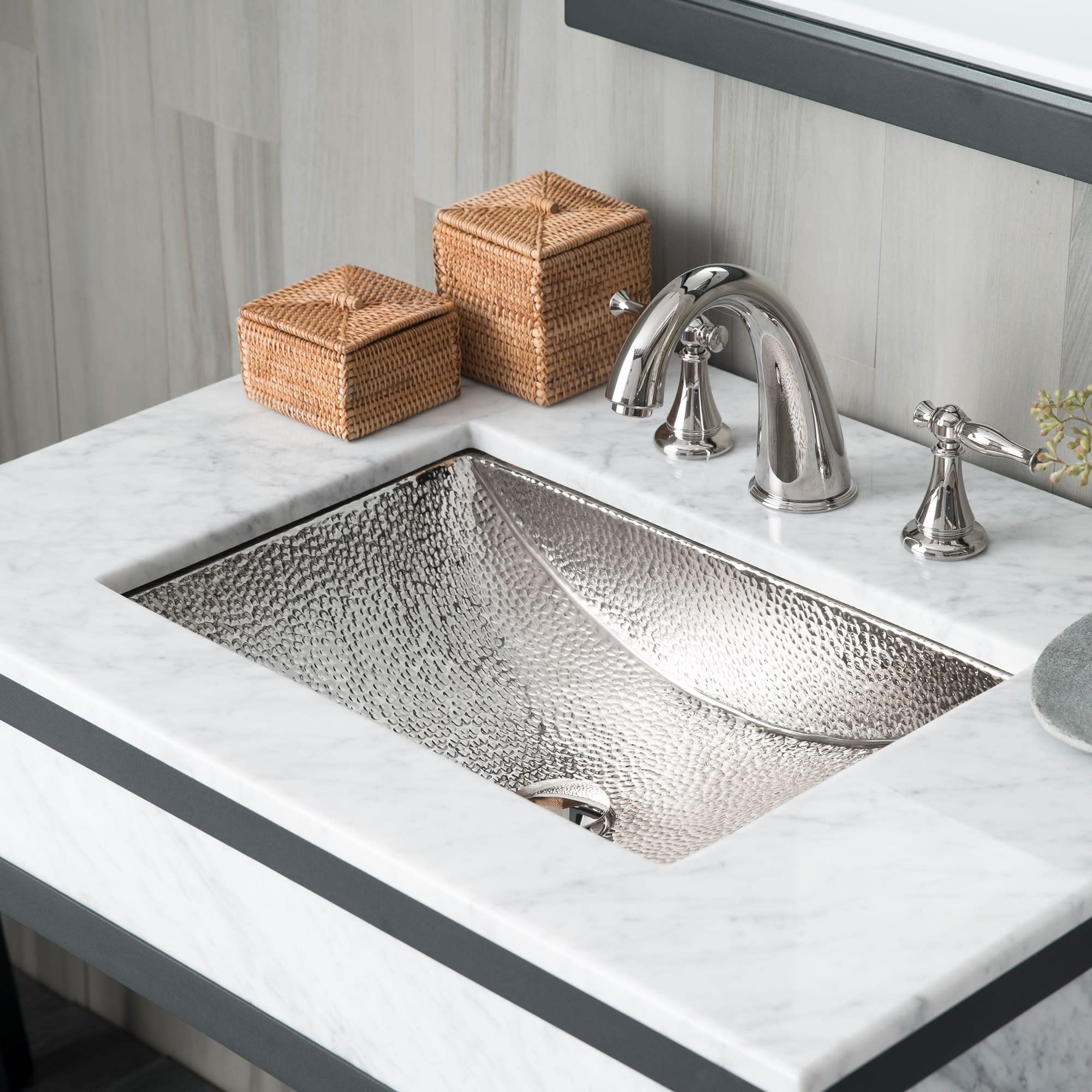 Polished copper undermount sink with hammered texture installed in white marble countertop with chrome faucet.