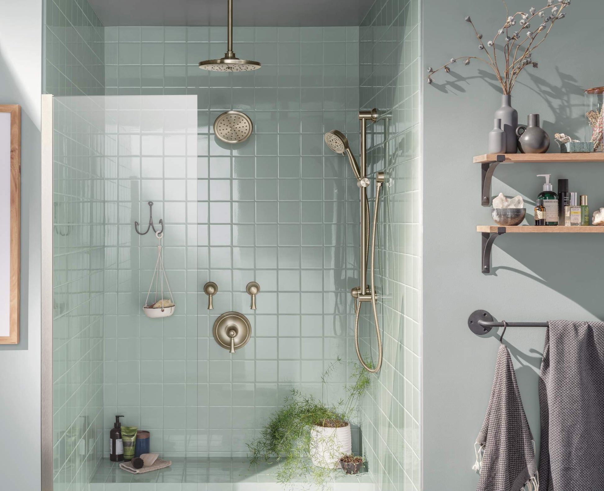 Brushed nickel shower valve trim with round volume control handle and two outlet ports installed in tiled shower wall.