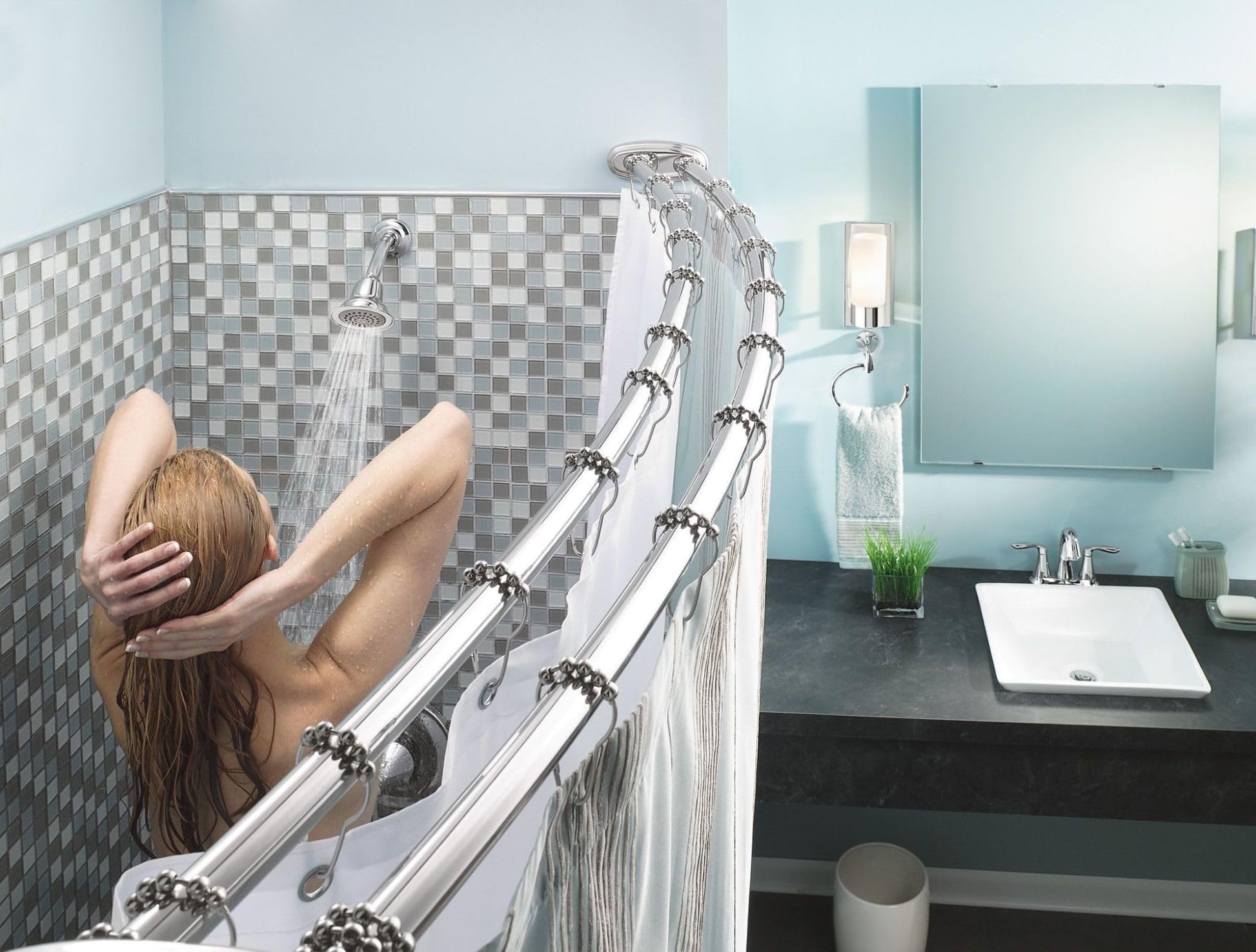 Chrome wall-mount towel ring installed above bathtub edge in bathroom with checkered tile surround.