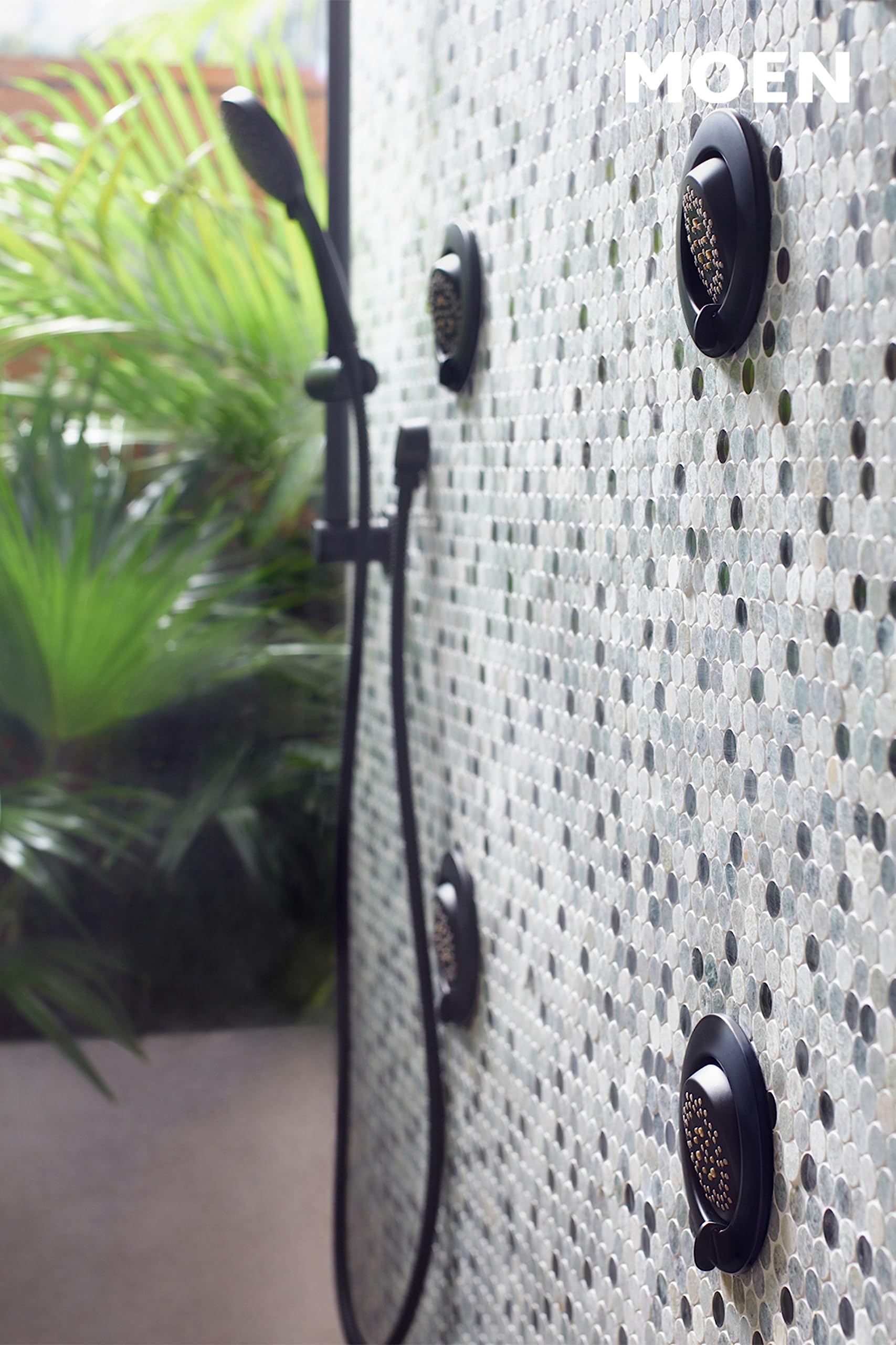 Matte black hand shower heads mounted on white tile wall with adjustable slide bar and hose.