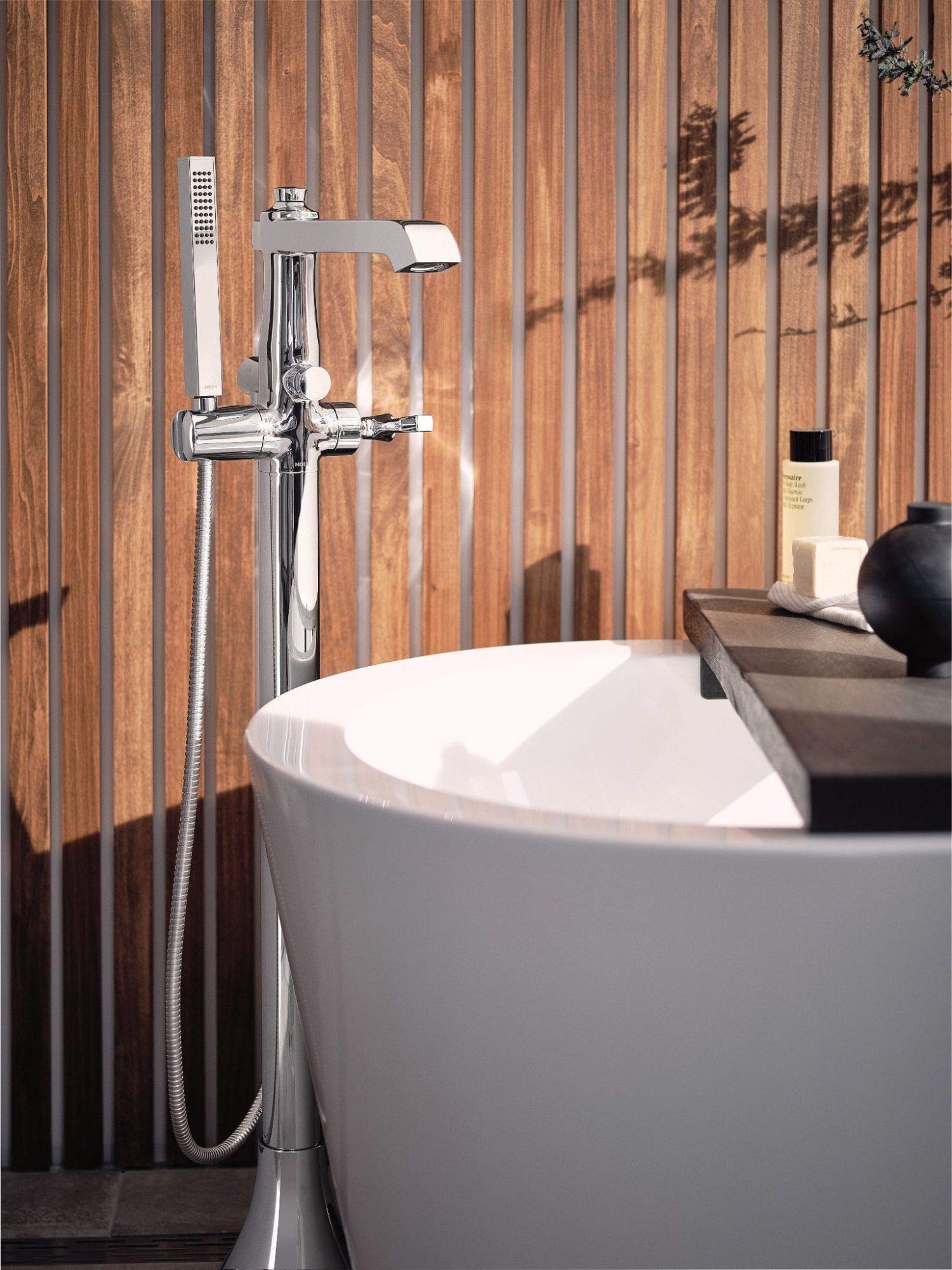 Polished nickel freestanding tub filler with single handle, curved spout, and detachable handheld showerhead on hose.