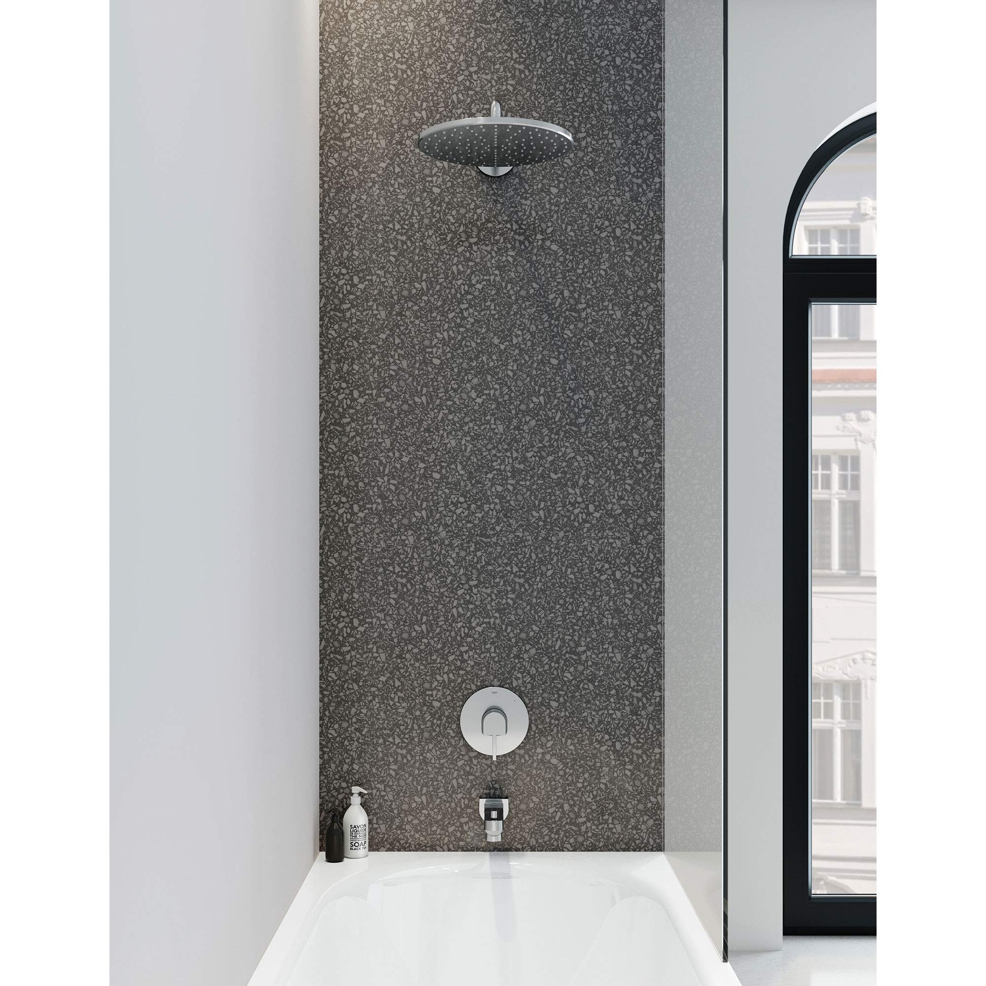 Chrome pressure balance valve trim with round showerhead and single control handle mounted on dark textured tile shower wall.