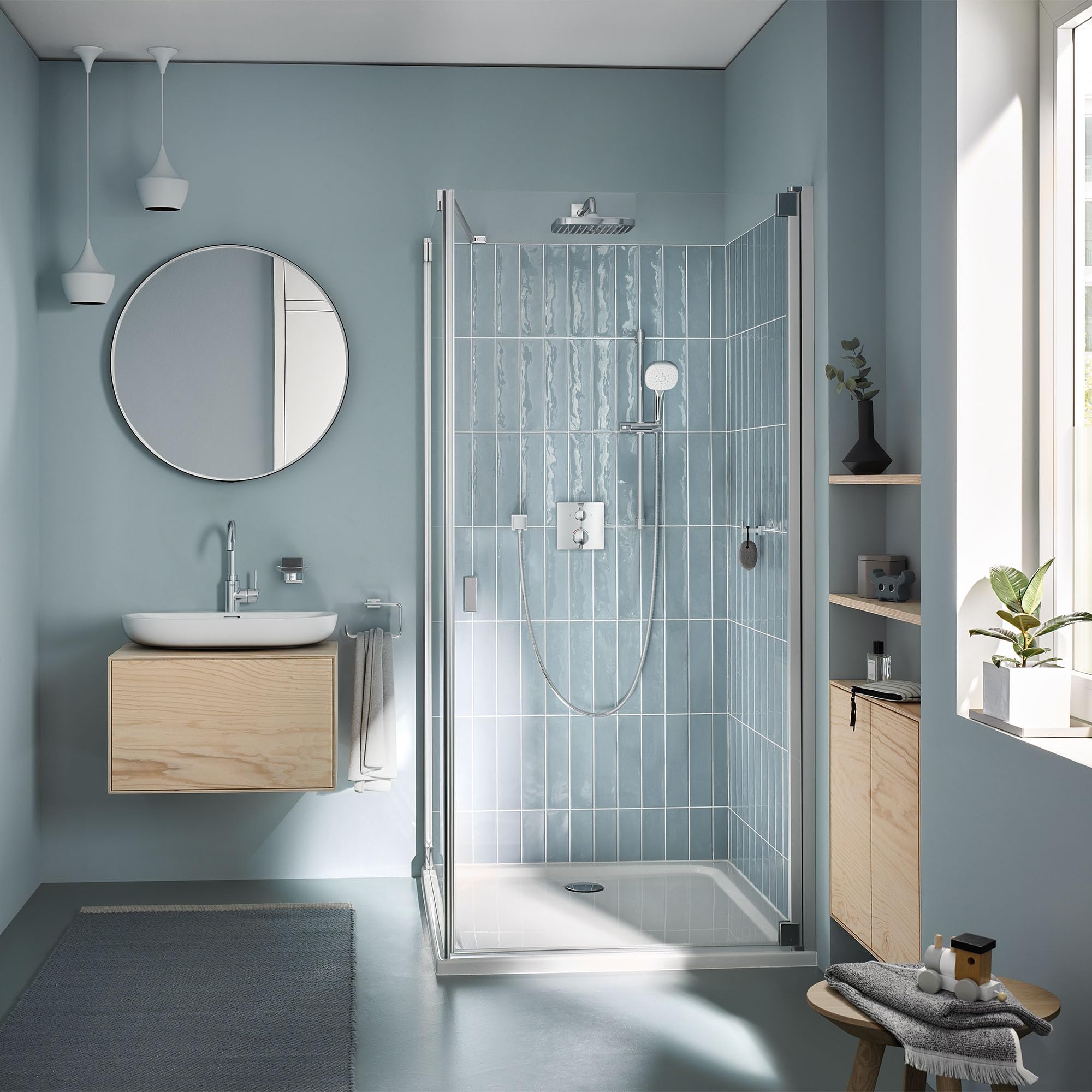 Chrome single-handle bathroom faucet with curved spout mounted on white round sink basin in light blue bathroom.