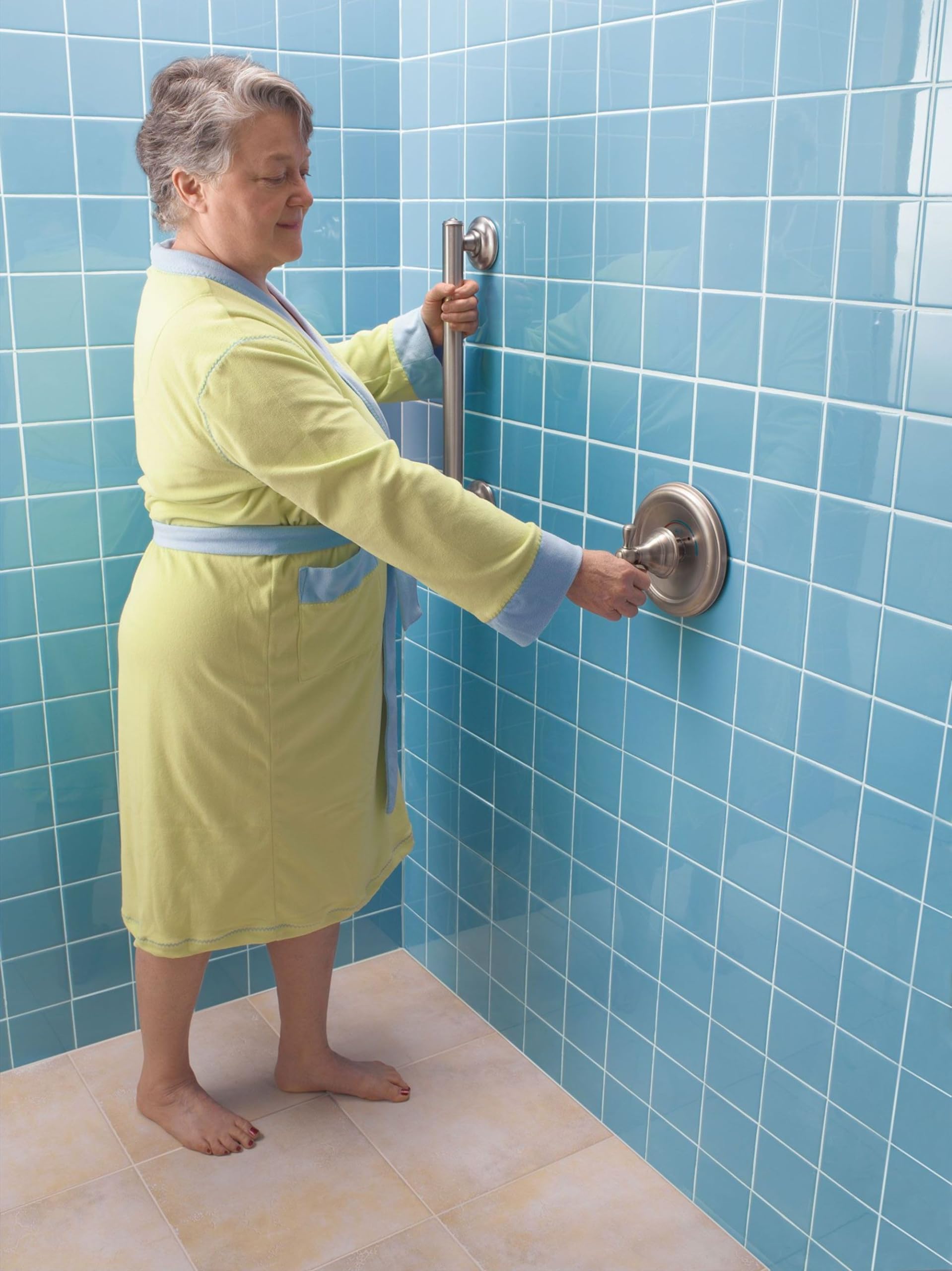 Stainless steel grab bar mounted horizontally on bathroom tile wall with person demonstrating grip.