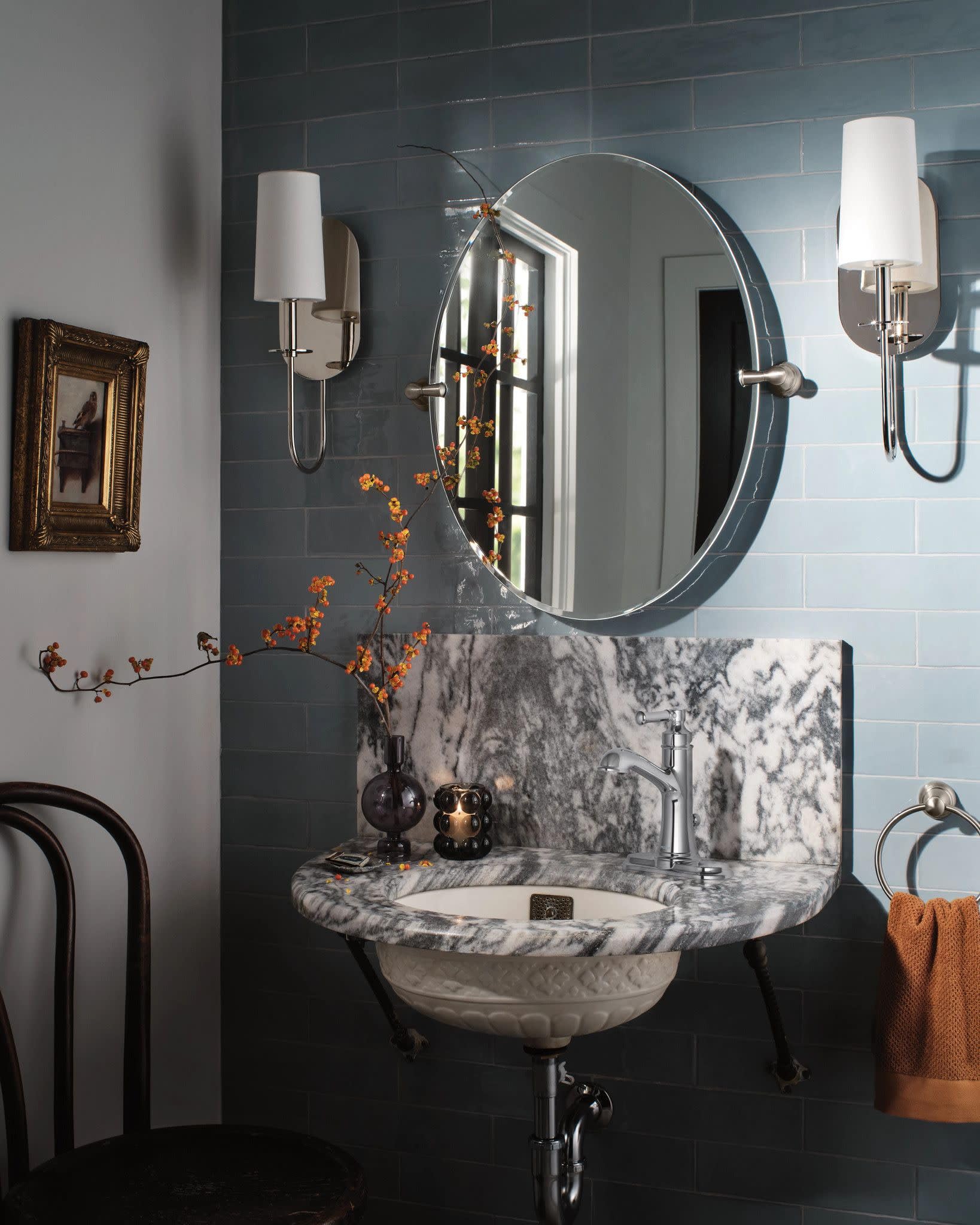 Chrome single-handle bathroom sink faucet with curved spout installed on marble sink counter.