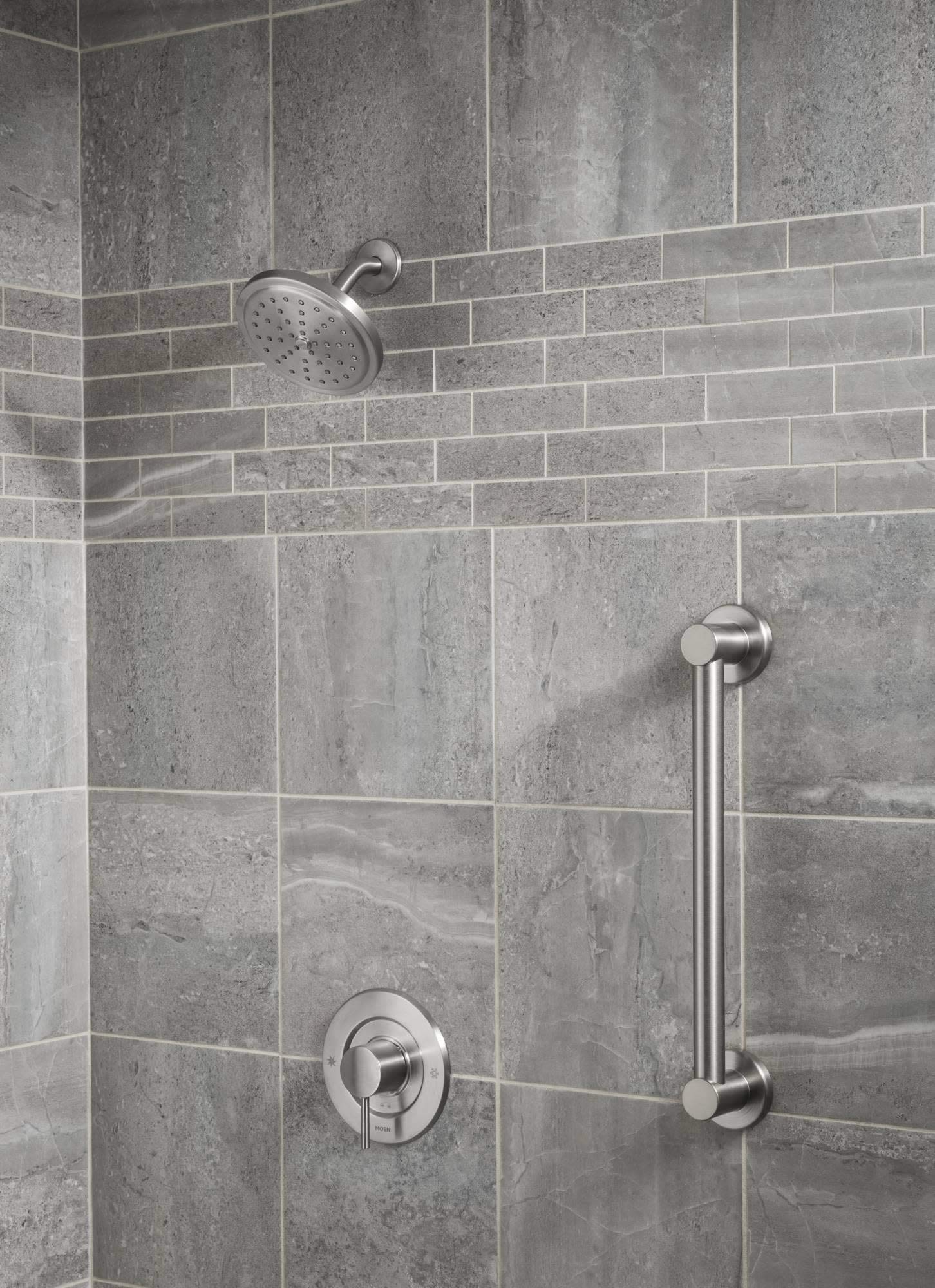 Brushed gold stainless steel grab bar mounted horizontally on tiled shower wall next to showerhead and valve controls.
