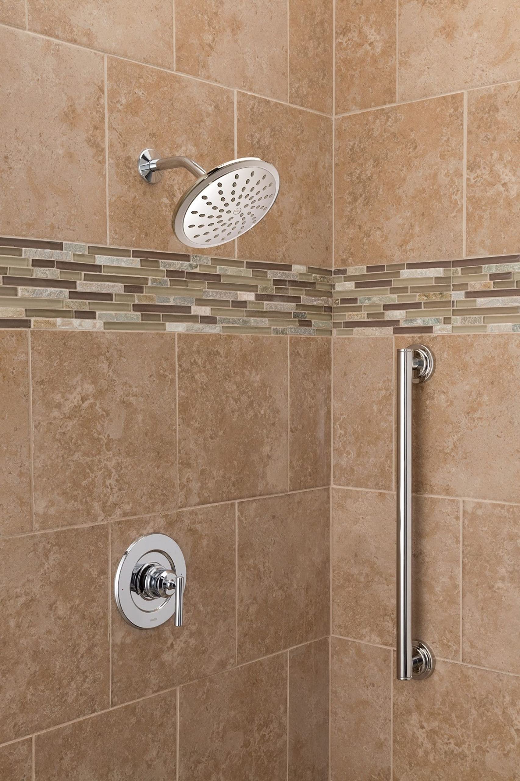 Chrome rain shower head with perforated spray pattern mounted on tiled shower wall with control valve below.